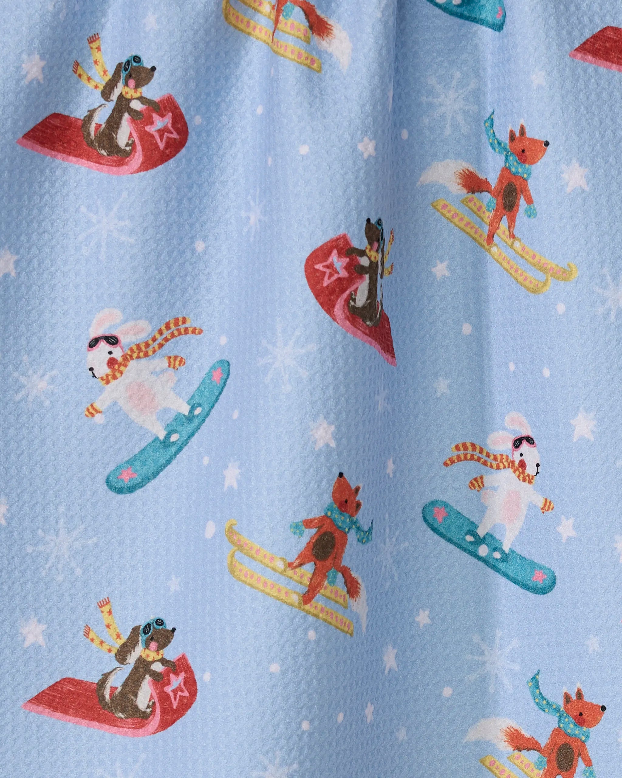 Winter Friends by Geometry features foxes and dogs in scarves and goggles, snowboarding and sledding amid snowflakes—a fun, eco-friendly tea towel for your kitchen.