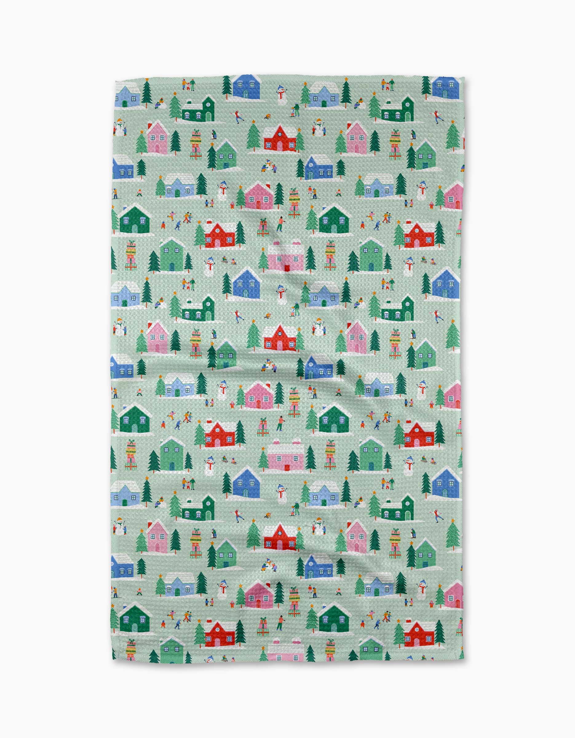 The Ceyda Alasar “Winter Magic” tea towel showcases a festive winter village with colorful houses, snowmen, and bundled-up people on a blue-green background. Made from recycled materials, it's quick-drying for everyday use.