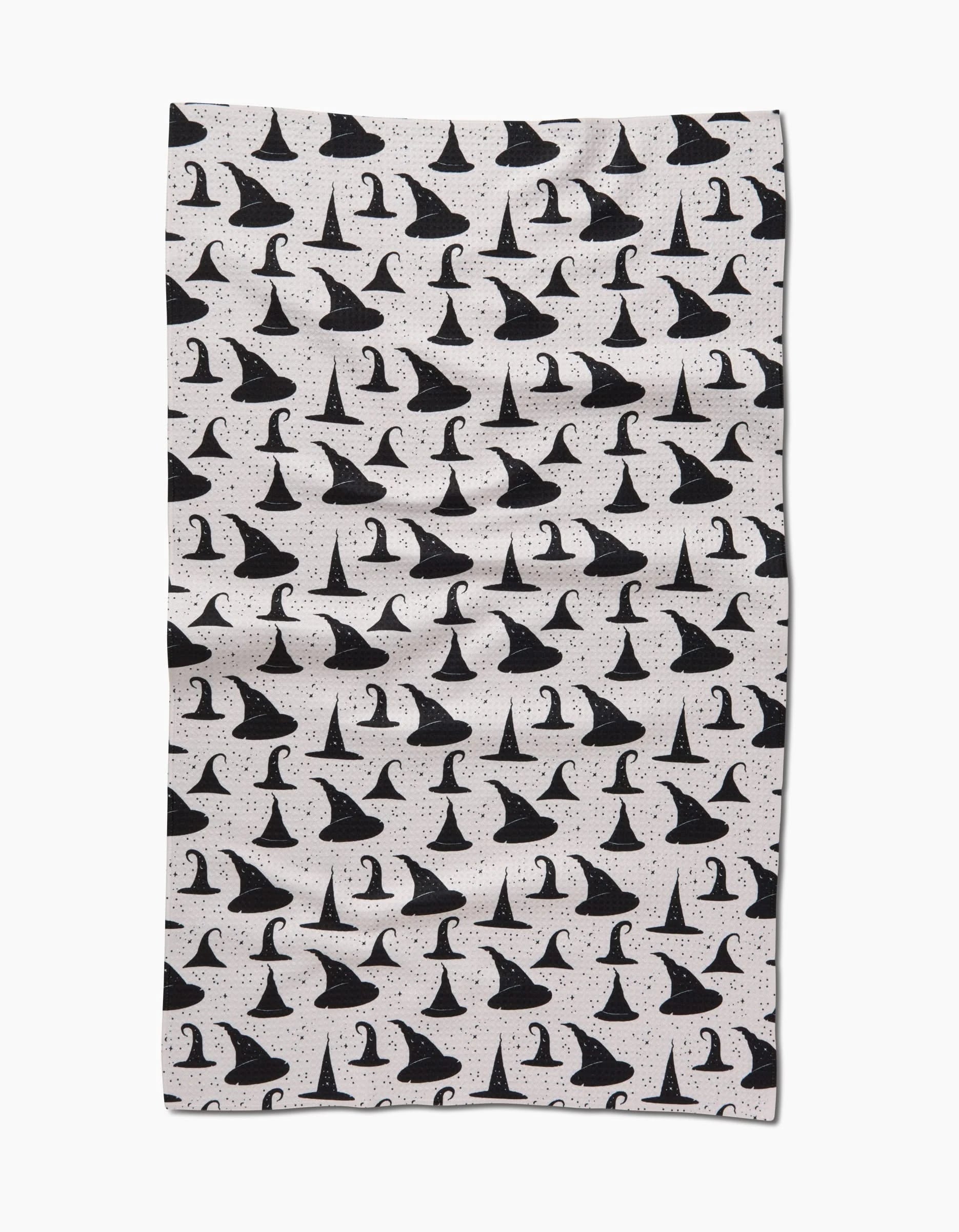 The Witchy Whims blanket by Danelys Sidron features black witch hats and sparkles on white, with each hat uniquely angled. Crafted from recycled materials, it offers a whimsical Halloween-themed design.