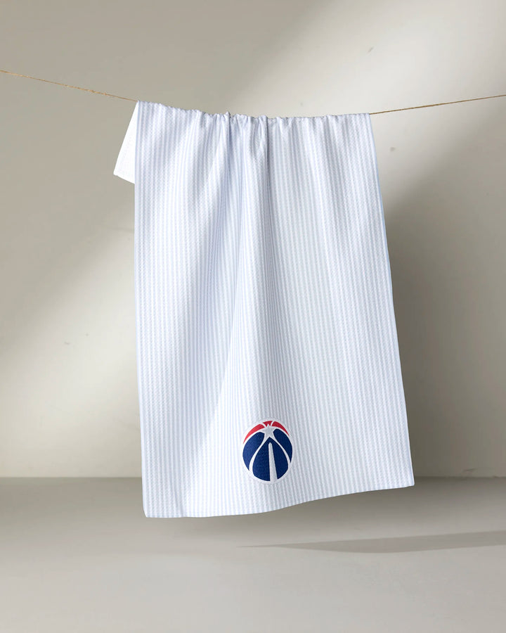 The NBALAB x Geometry "Wizards Classic" is a white, sustainable kitchen towel with subtle blue pinstripes and a stylized basketball logo in the Washington Wizards’ red, white, and blue near the bottom.