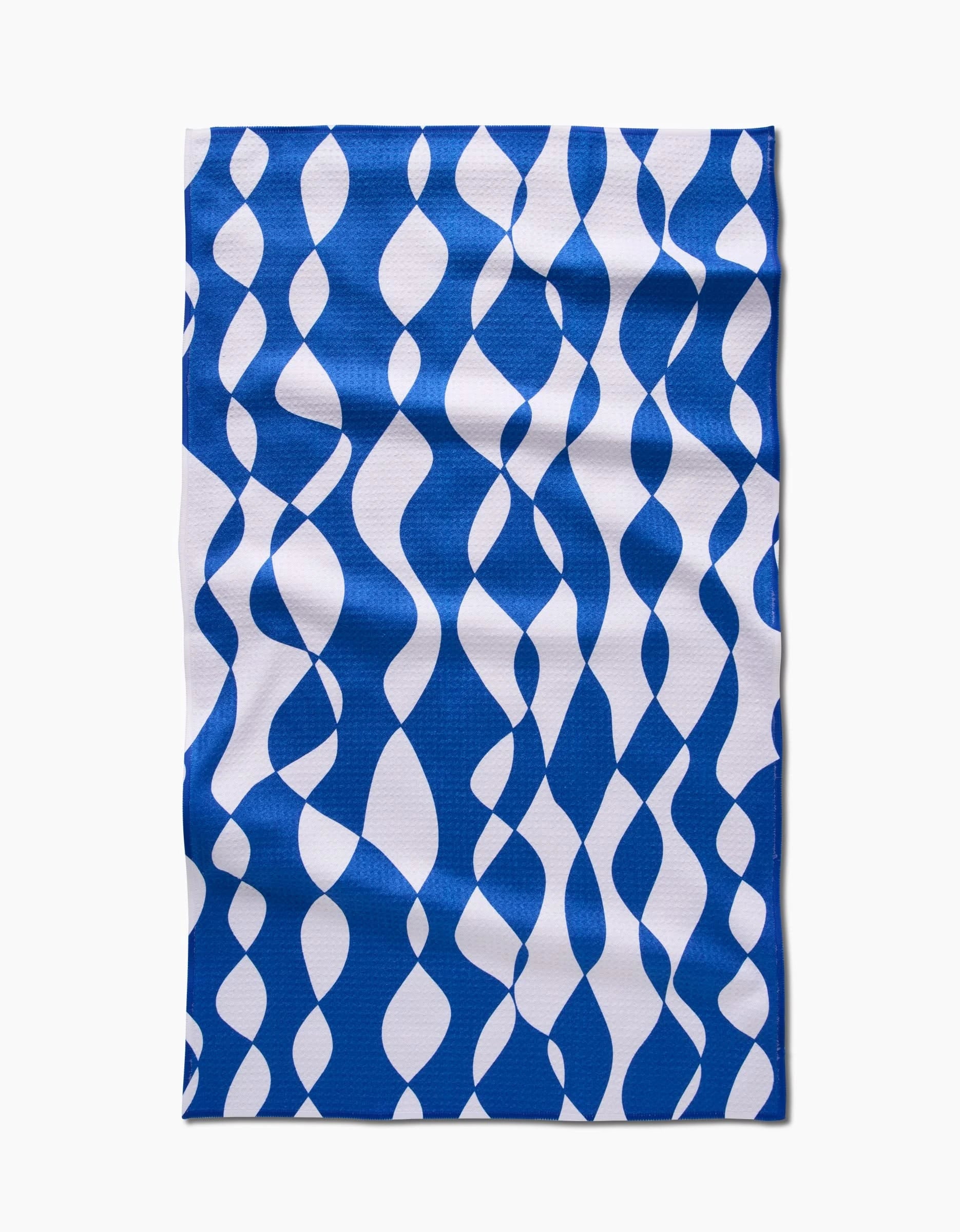 The Claire Iglesias Wonky Lines tea towel features a blue and white wavy ribbon pattern on durable Geoweave fabric, shown laid flat on a white background.
