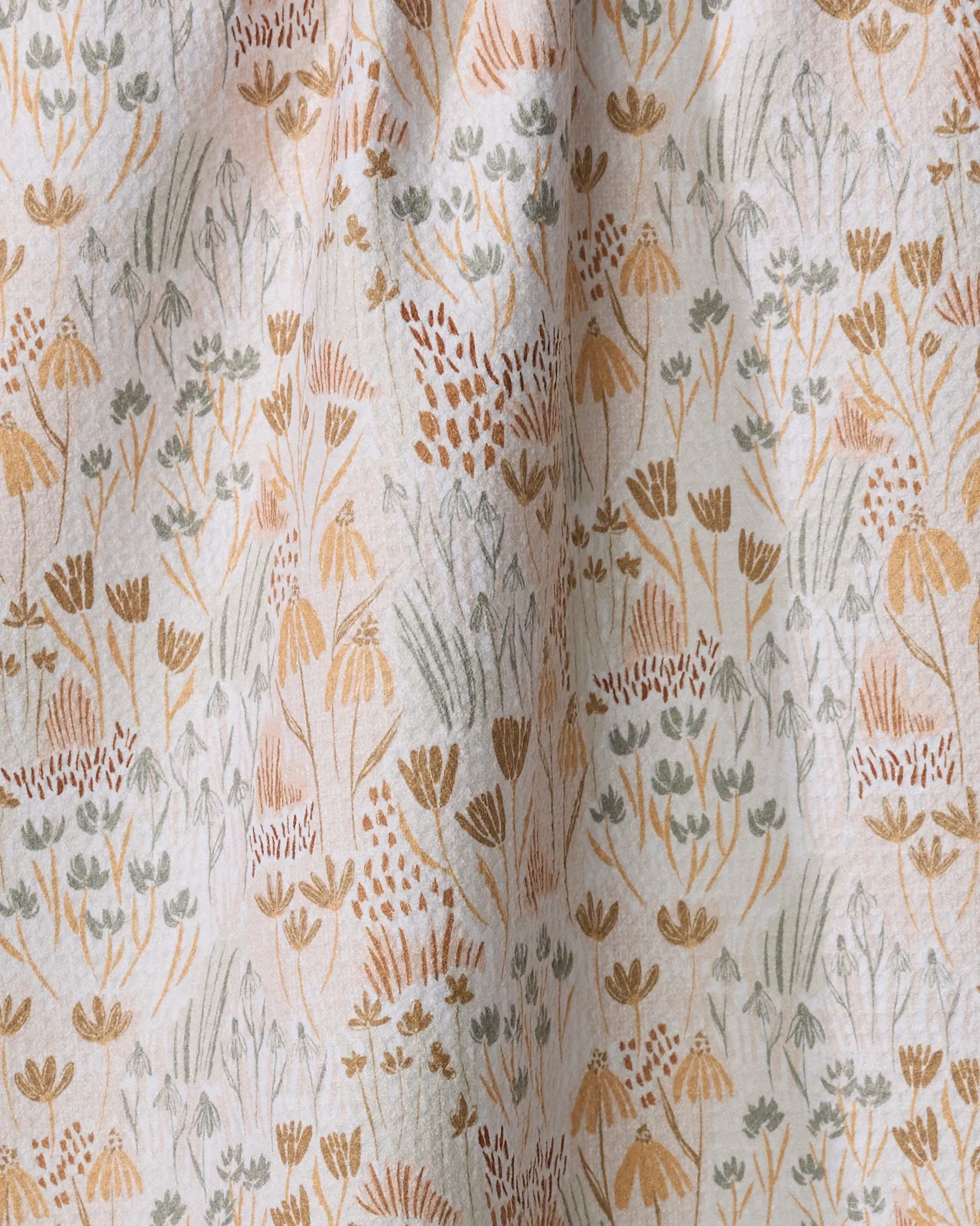 A close-up of Hufton Studio's Woodland Floral recycled kitchen towel, showcasing a botanical pattern with delicate flowers, leaves, and grasses in muted browns, golds, and greens on a light beige background.