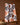 The Geometry Woodland Waltz kitchen tea towel, made from recycled materials, showcases orange and black leaf and pinecone patterns. It hangs above a brown background with pinecones and wooden slices arranged below.