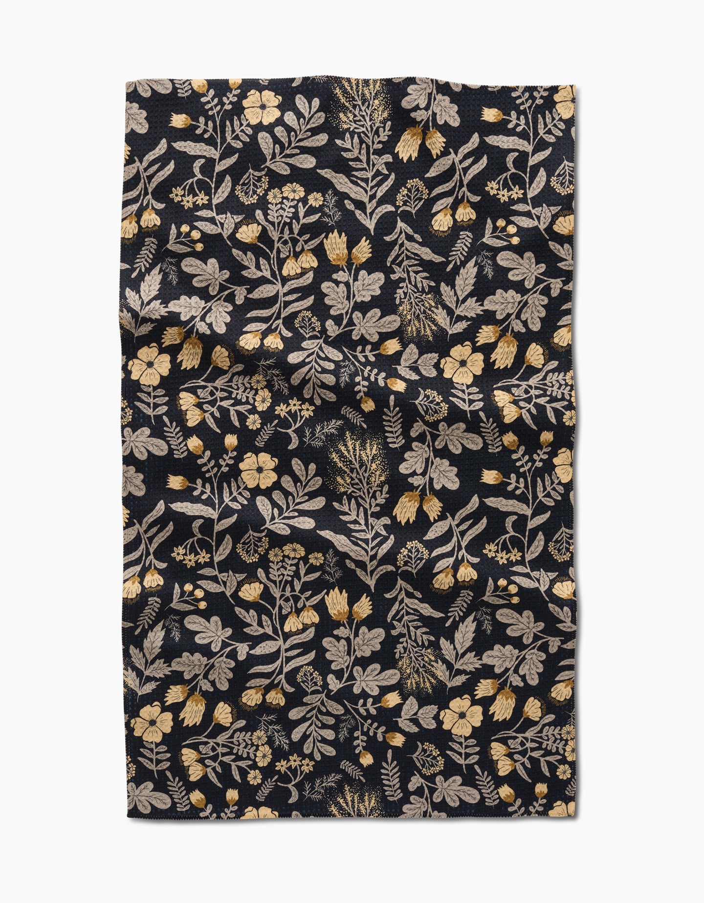 The Danelys Sidron Woodland Wildflowers tea towel is a dark rectangular cloth with yellow and cream floral botanical patterns, made from recycled materials. The slightly wrinkled fabric is shown flat on a white background.