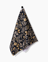 The Danelys Sidron Woodland Wildflowers hanging tea towel features a dark floral and leaf pattern in beige and gold on ultra-absorbent recycled fabric, shown against a white background.