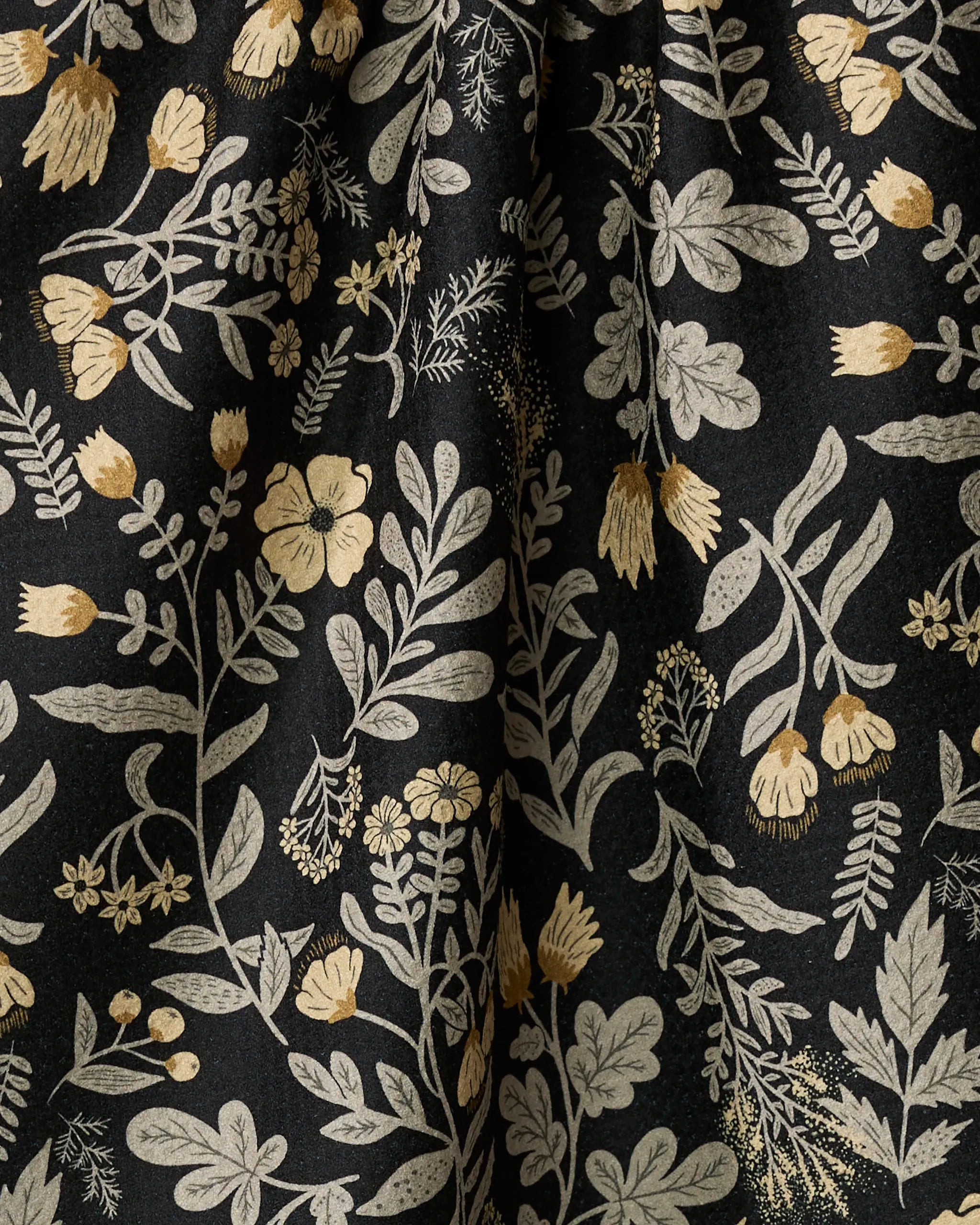 The Woodland Wildflowers towel by Danelys Sidron features ultra-absorbent black fabric adorned with beige and gold botanical motifs in a natural, hand-drawn style—perfect for your kitchen.