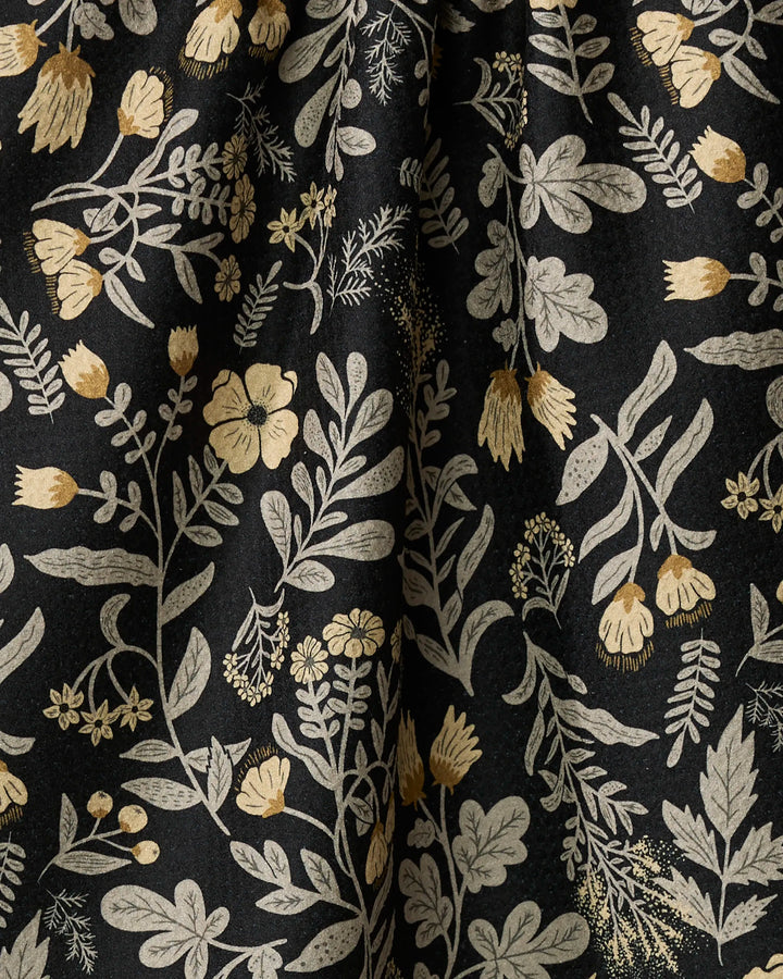 The Woodland Wildflowers towel by Danelys Sidron features ultra-absorbent black fabric adorned with beige and gold botanical motifs in a natural, hand-drawn style—perfect for your kitchen.