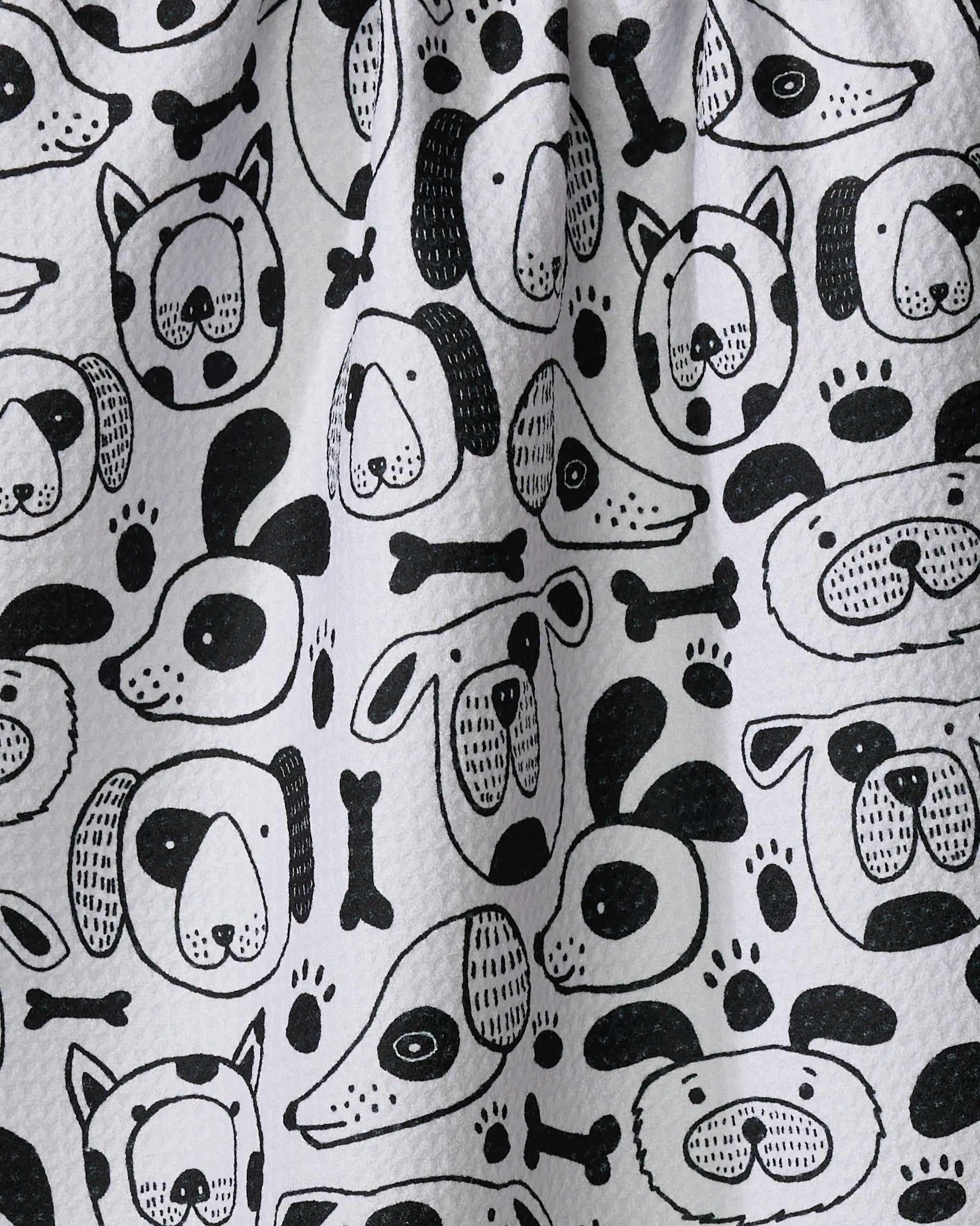 The "Woofin Around" kitchen towel by Jessica Swift features playful black and white cartoon dog faces, bones, and paw prints. Eco-friendly and charming, its whimsical design brightens your daily routine.