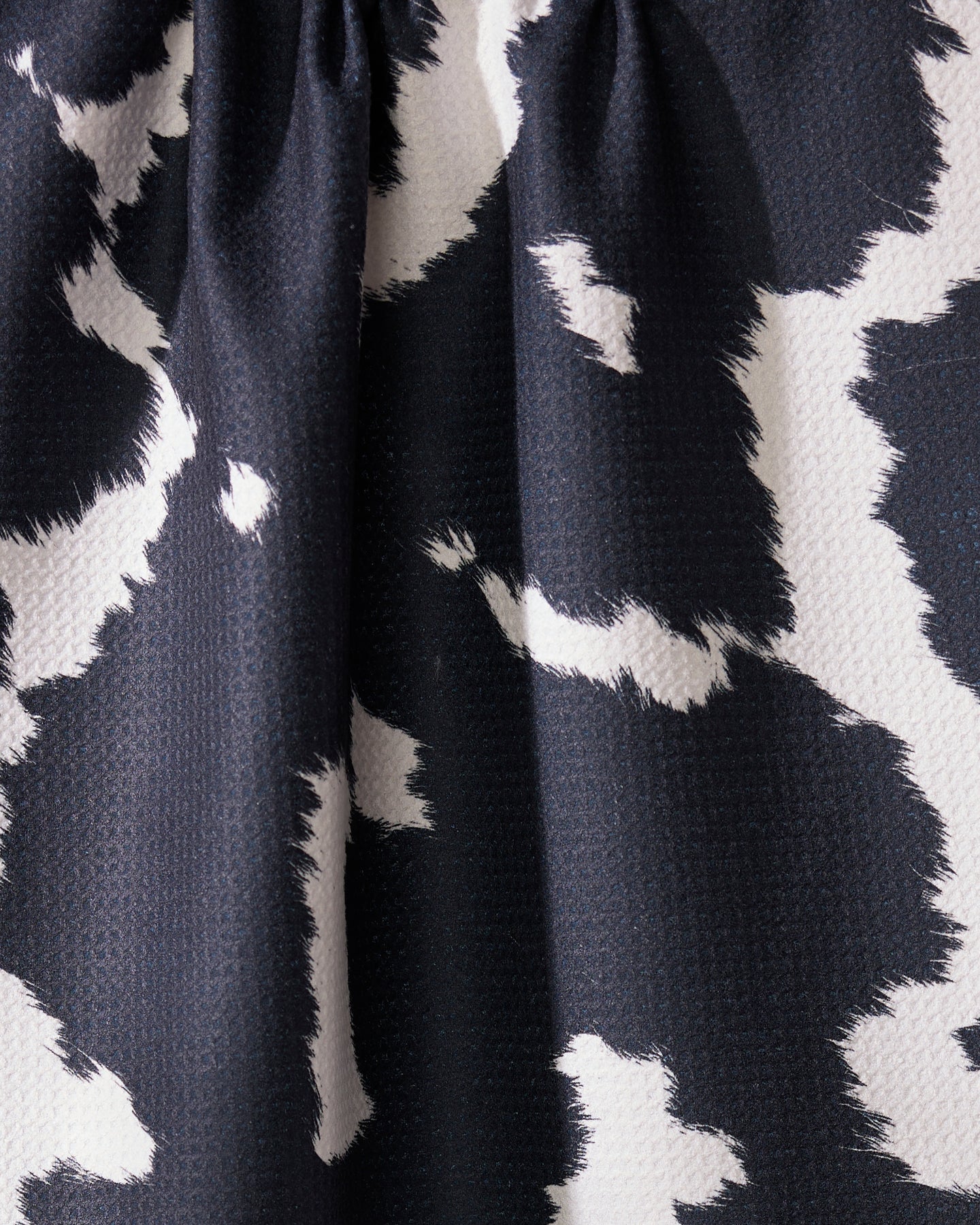 A close-up of Wrangler by Geometry shows black and white fabric with an abstract, irregular pattern. Made from recycled materials, the fabric is slightly gathered at the top, creating soft folds and shadows.