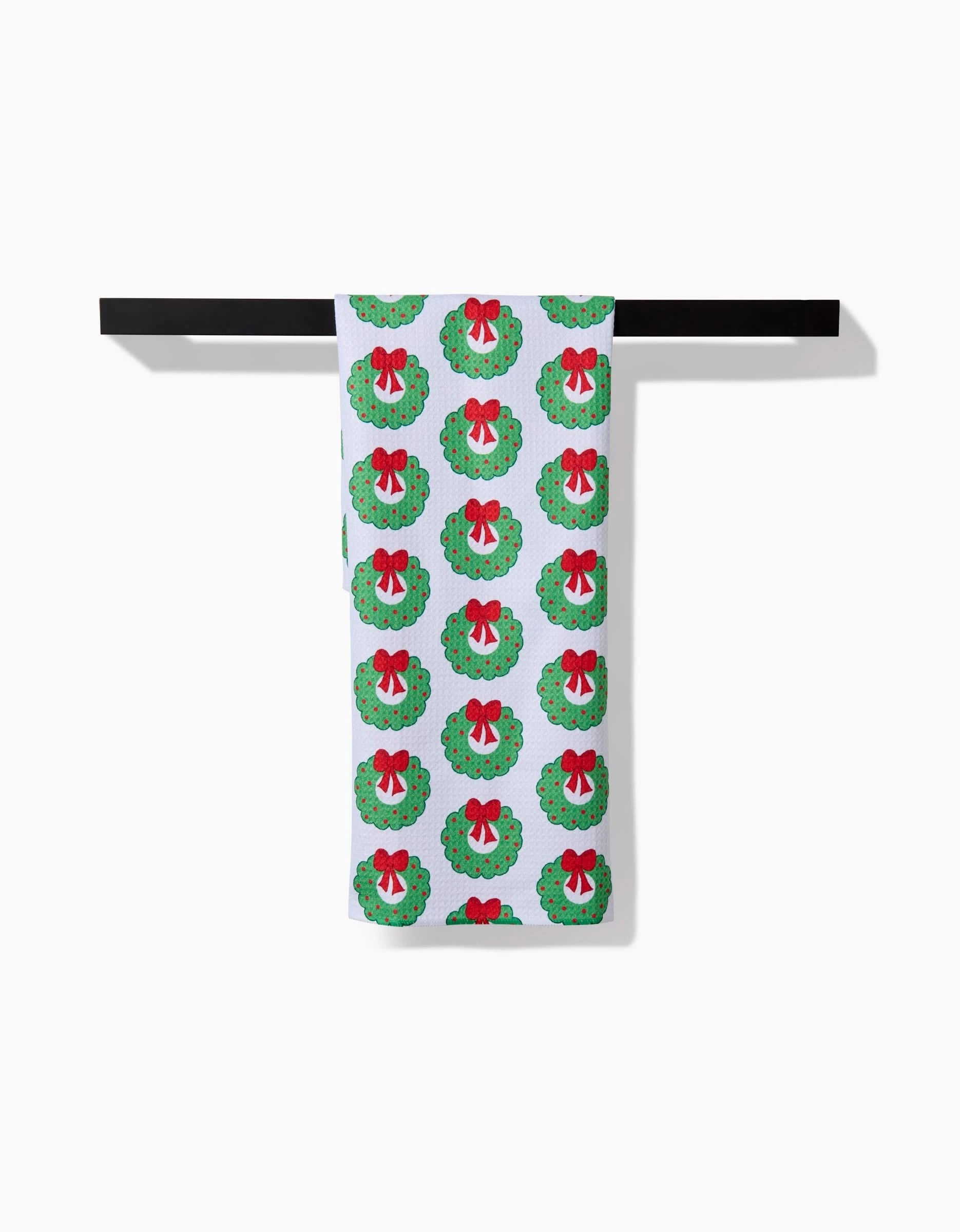 The Mindfulnice Wreath Wishes white tea towel features green Christmas wreaths with red bows on a black rod. Ultra-absorbent and festive, its the perfect functional touch for your holiday kitchen.