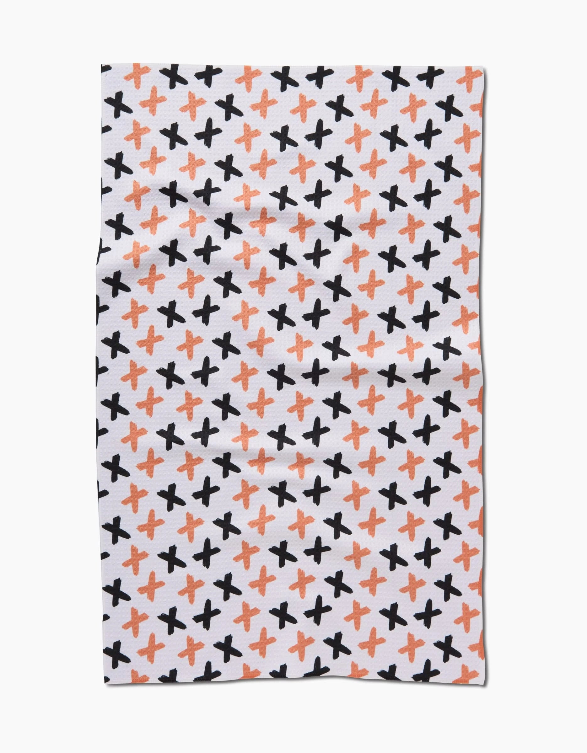 The X Marks The Spot Orange tea towel by Charlie Rowan Designs features a diagonal repeat of black and orange X shapes across a white background.