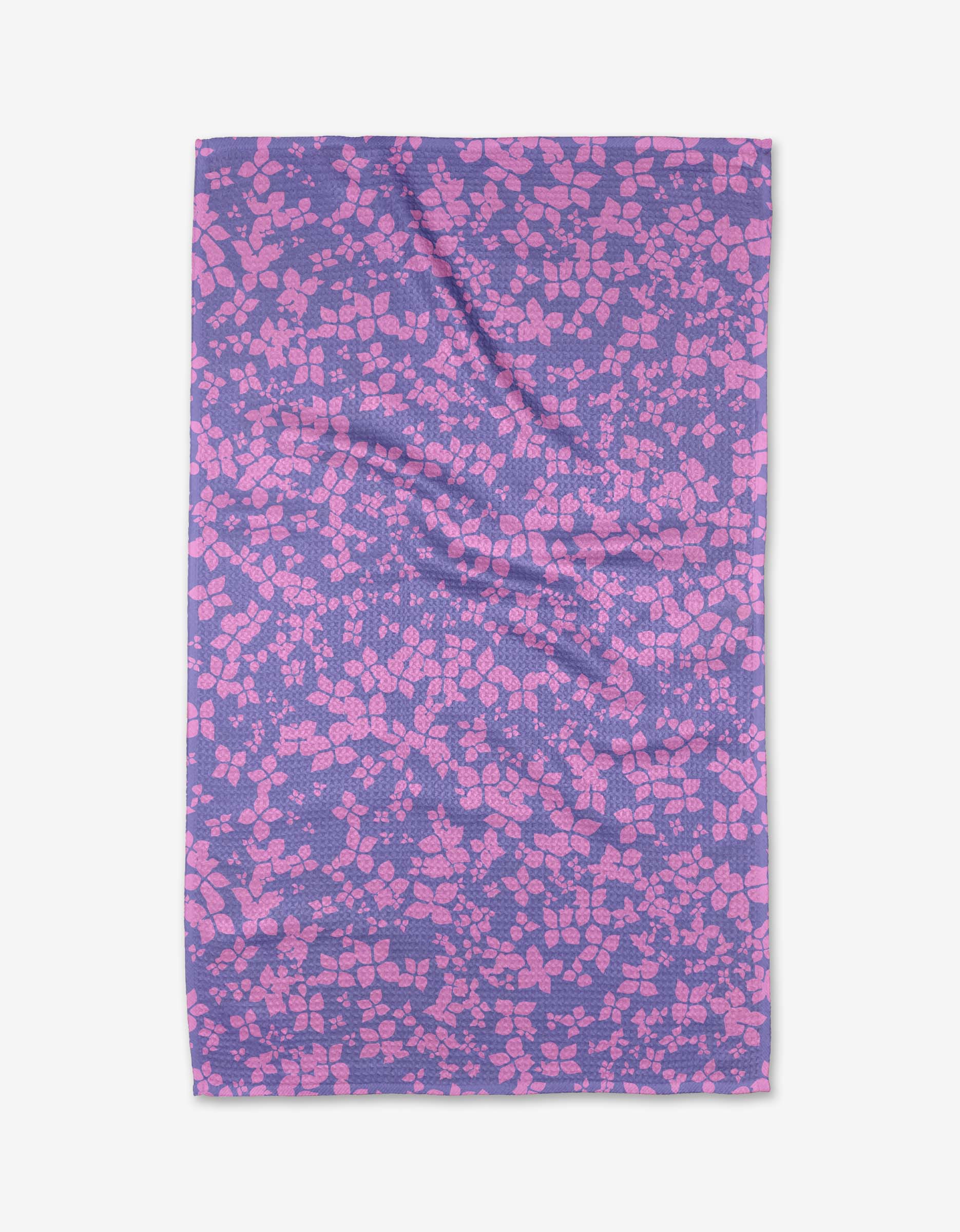 The Sareka Unique You Give Me Butterflies tea towel features a purple background with pink geometric shapes in a mosaic pattern. Made from Geoweave™ fabric, it has some wrinkles and is shown laid flat on a white surface.