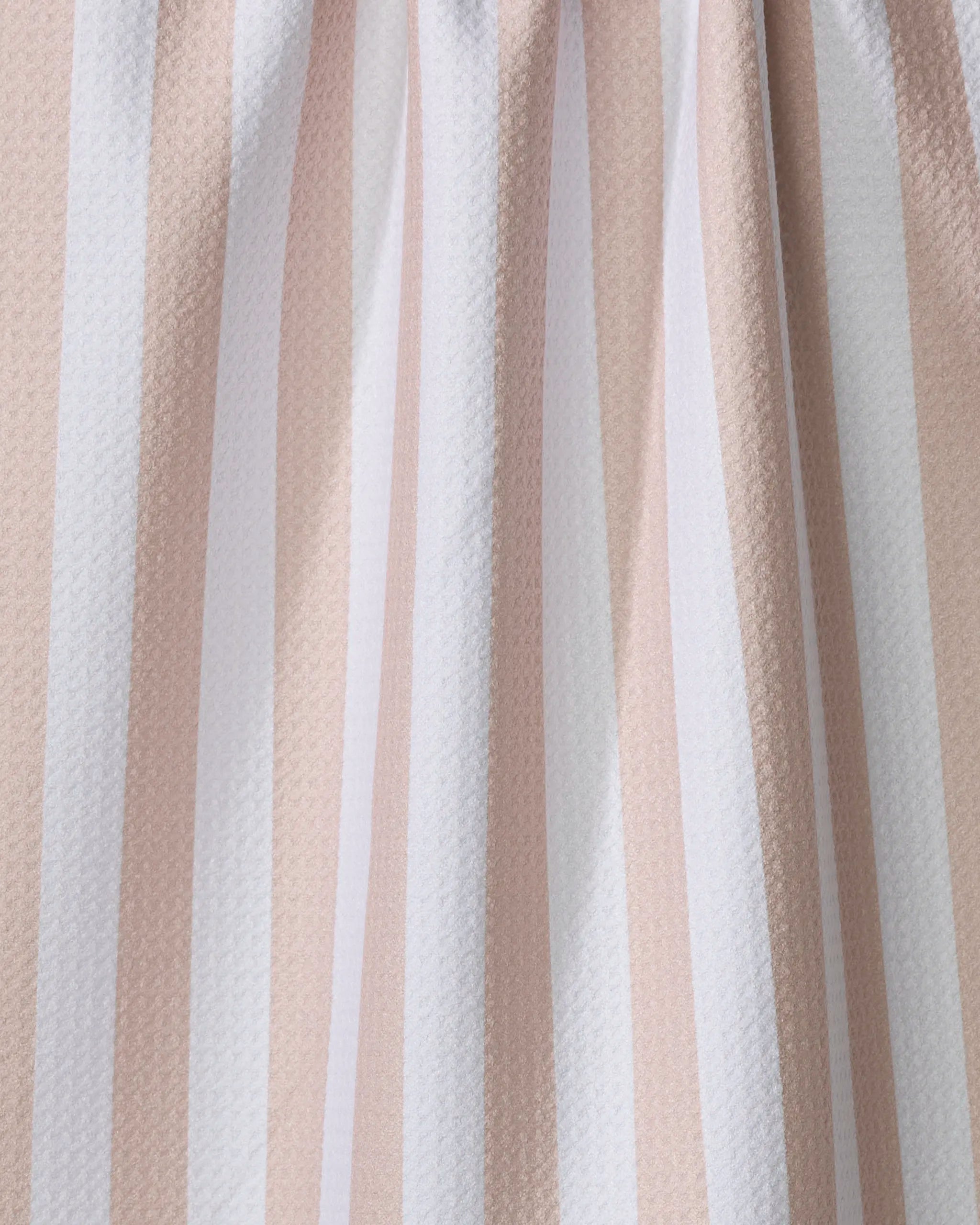 Close-up of the Kailee Wright Yvonne Stripe kitchen towel, featuring vertical beige and white stripes, a slightly textured surface, gentle folds, and crafted from recycled materials.