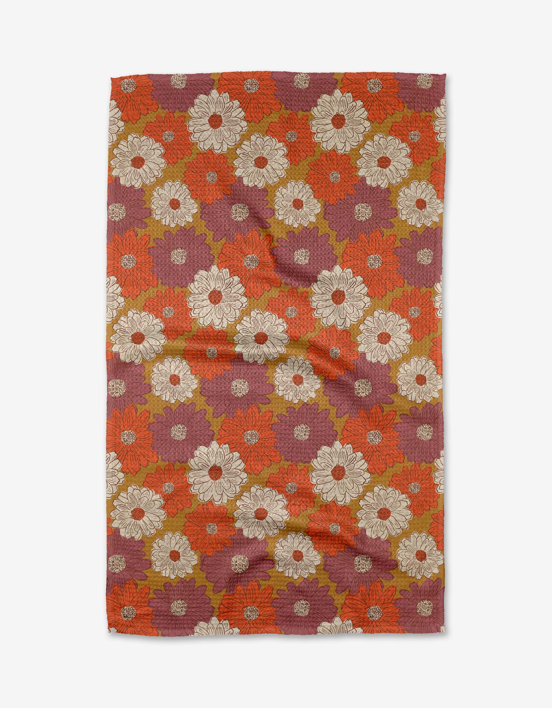 The Zinnia Forever tea towel by Kayla Ann features a retro floral design with bold white, orange, red, and olive green flowers on a reddish-purple background. Made from recycled materials, the fabric may display slight wrinkles.