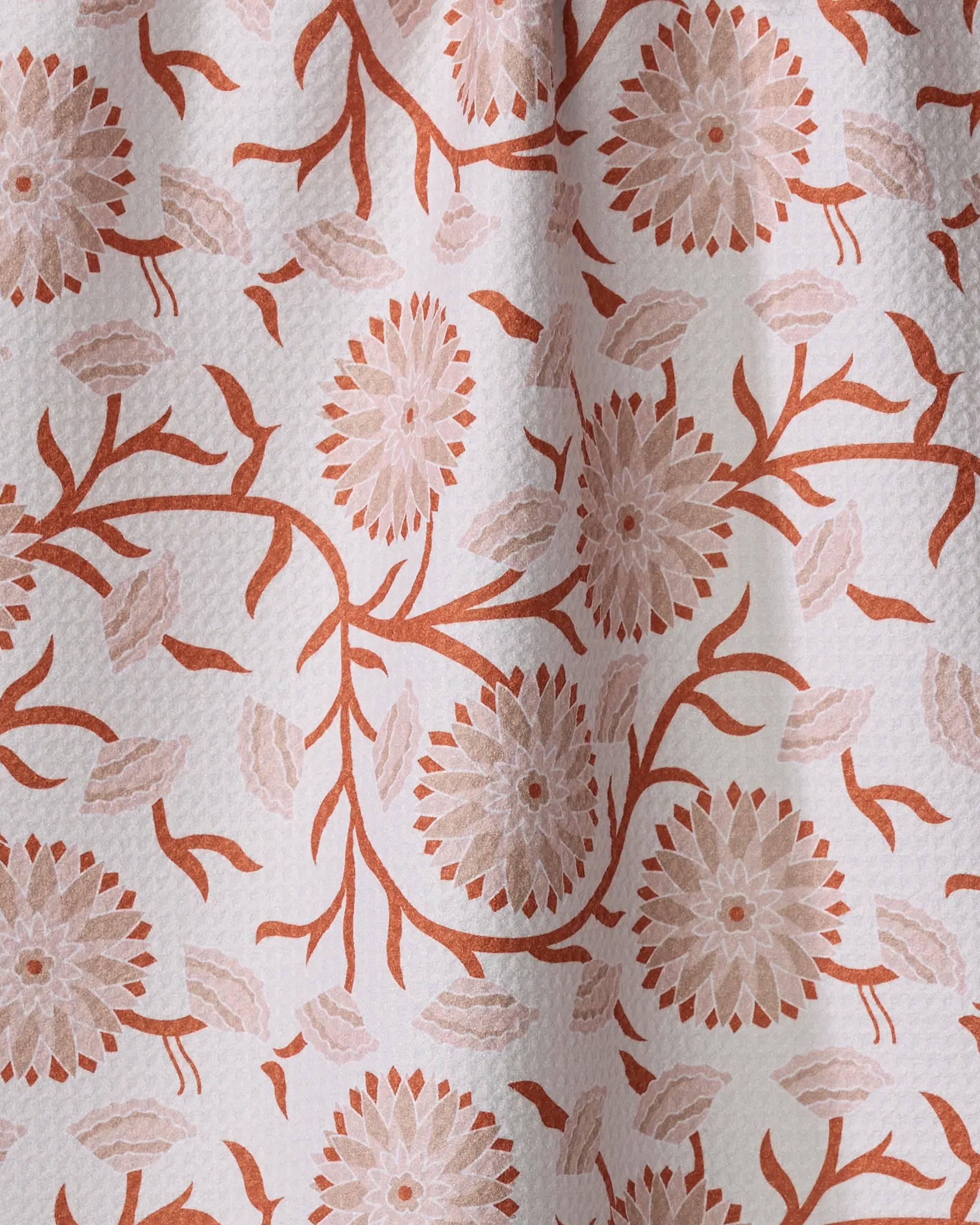 A close-up of Dabney Lee’s Zinnie tea towel made from recycled Geoweave fabric, featuring a textured floral pattern with large terracotta and beige flowers and leaves on white.