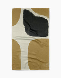 Geometrys Bend tea towel is a rectangular, ultra-absorbent piece featuring an abstract design with beige, tan, white, and a bold black brushstroke. Curved color blocks add a modern flair.