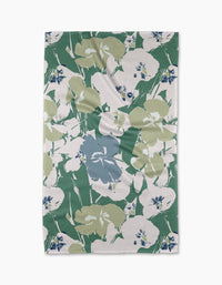 The Geometry Brie tea towel is rectangular and features a floral pattern with large green, blue, and white flowers and leaves on a white background. The cloth may display minor wrinkles.