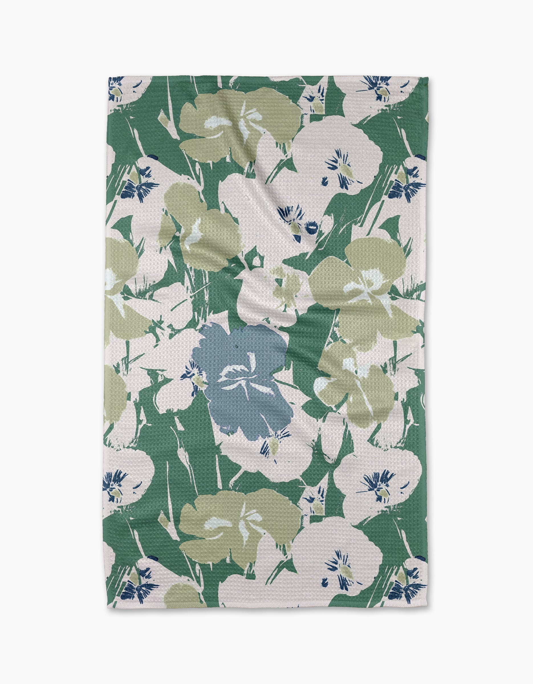 The Geometry Brie tea towel is rectangular and features a floral pattern with large green, blue, and white flowers and leaves on a white background. The cloth may display minor wrinkles.
