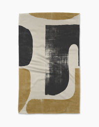 The Forma woven blanket by Geometry showcases bold black and mustard yellow curved shapes on a cream background, inspired by eco-friendly minimalist kitchen towels.