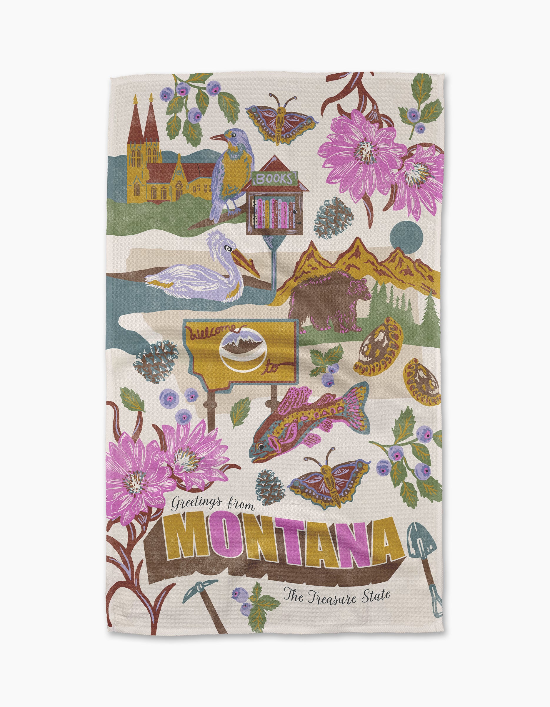 The Geometry Greetings From Montana tea towel features vibrant Geoweave fabric with illustrations of Montana’s symbols, landmarks, and wildlife, plus the text “Greetings from Montana, The Treasure State.”.