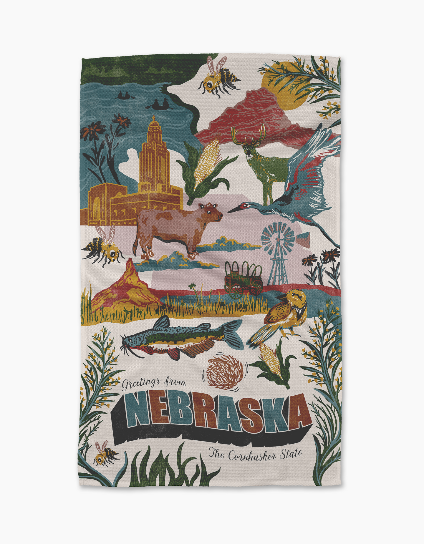 Geometry’s “Greetings From Nebraska” tea towel showcases Nebraska landmarks, native animals, and plants with vibrant images of wildlife, buildings, windmills, and farmland. “Greetings from Nebraska, The Cornhusker State” is written at the bottom.