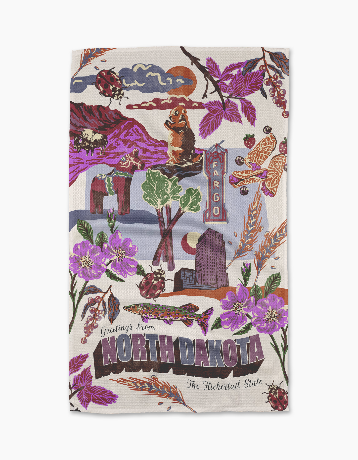 Geometry’s “Greetings From North Dakota” tea towel is illustrated with landmarks, purple flowers, ladybugs, a flickertail gopher, and a Fargo street sign. Made from recycled materials, it features “The Flickertail State” greeting.