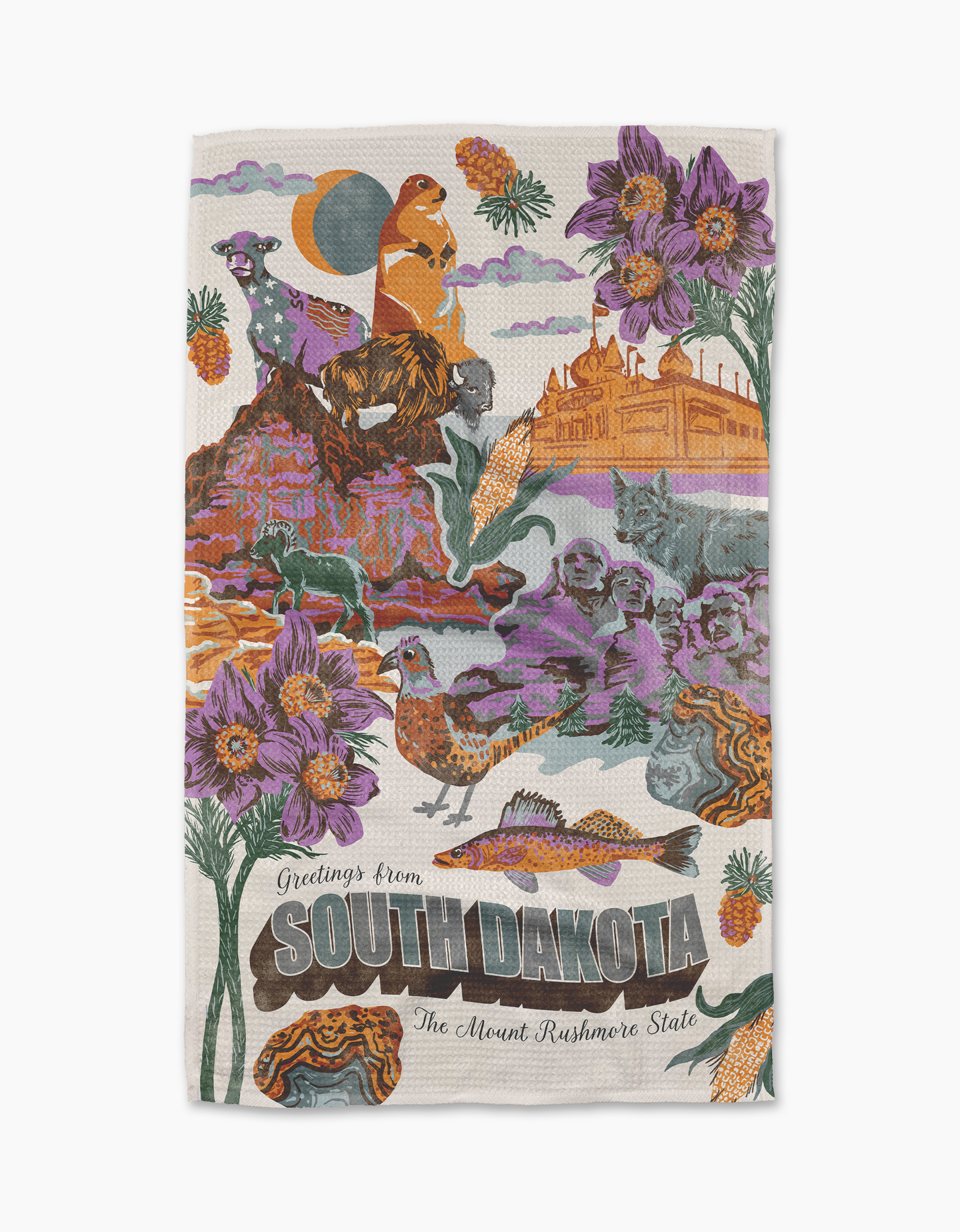 The Geometry Greetings From South Dakota tea towel features colorful illustrated wildlife, landmarks, purple flowers, and bold text like “Greetings from SOUTH DAKOTA” and “The Mount Rushmore State” on eco-friendly fabric.
