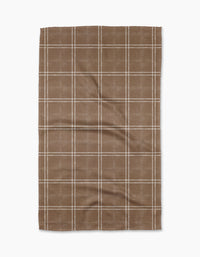 The Geometry Hearth Chestnut is a brown kitchen tea towel with a white checkered grid, laid flat on a white background. Made from recycled materials, its fabric is slightly textured with visible creases.