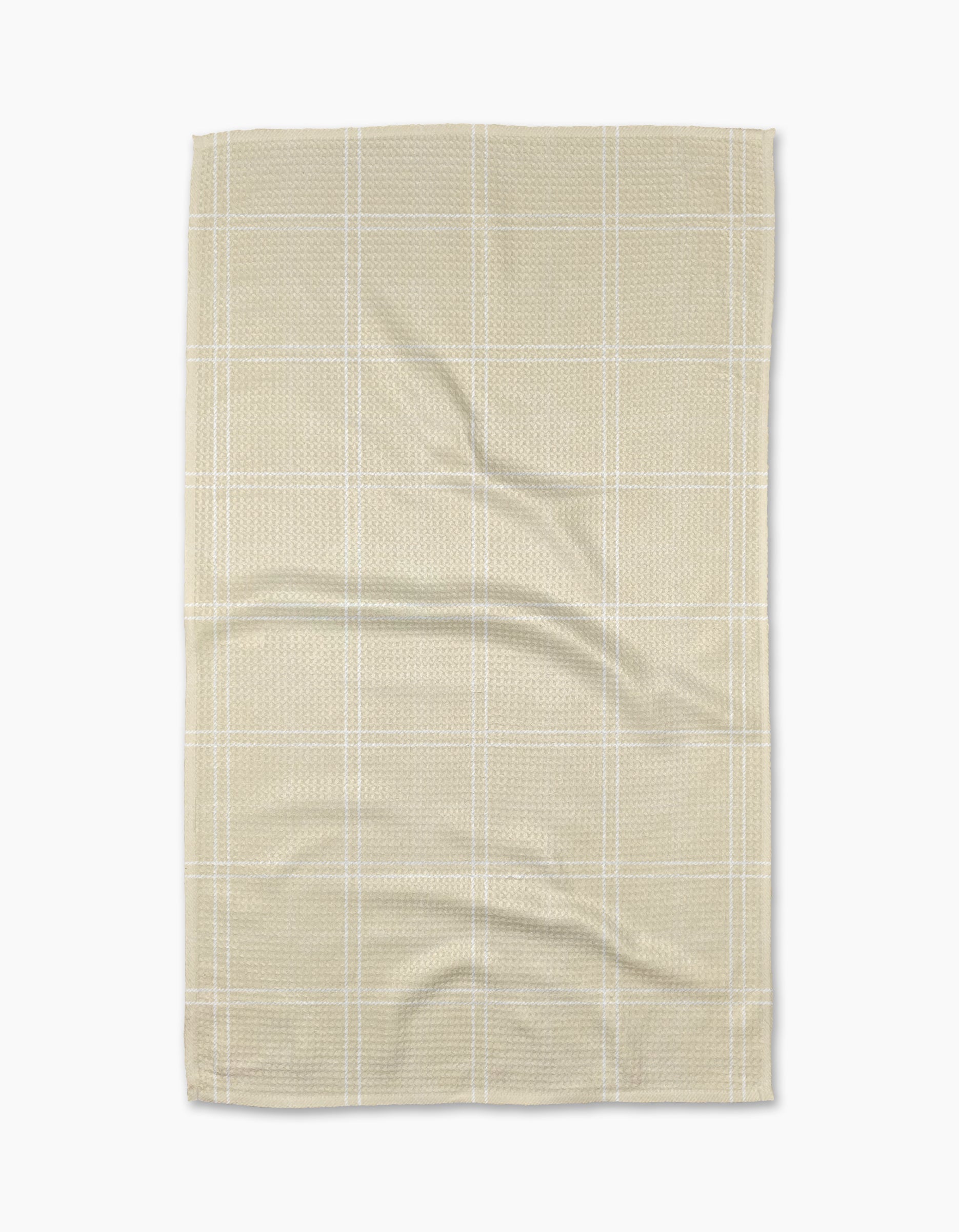 The Geometry Hearth Oat tea towel features a subtle white checkered pattern on beige recycled fabric, displayed flat with soft folds and creases against a white background.