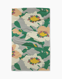 The Geometry Isla tea towel features large white, pink, and yellow flowers with green leaves on a light gray background. Its textured fabric offers both style and practicality for daily kitchen use.
