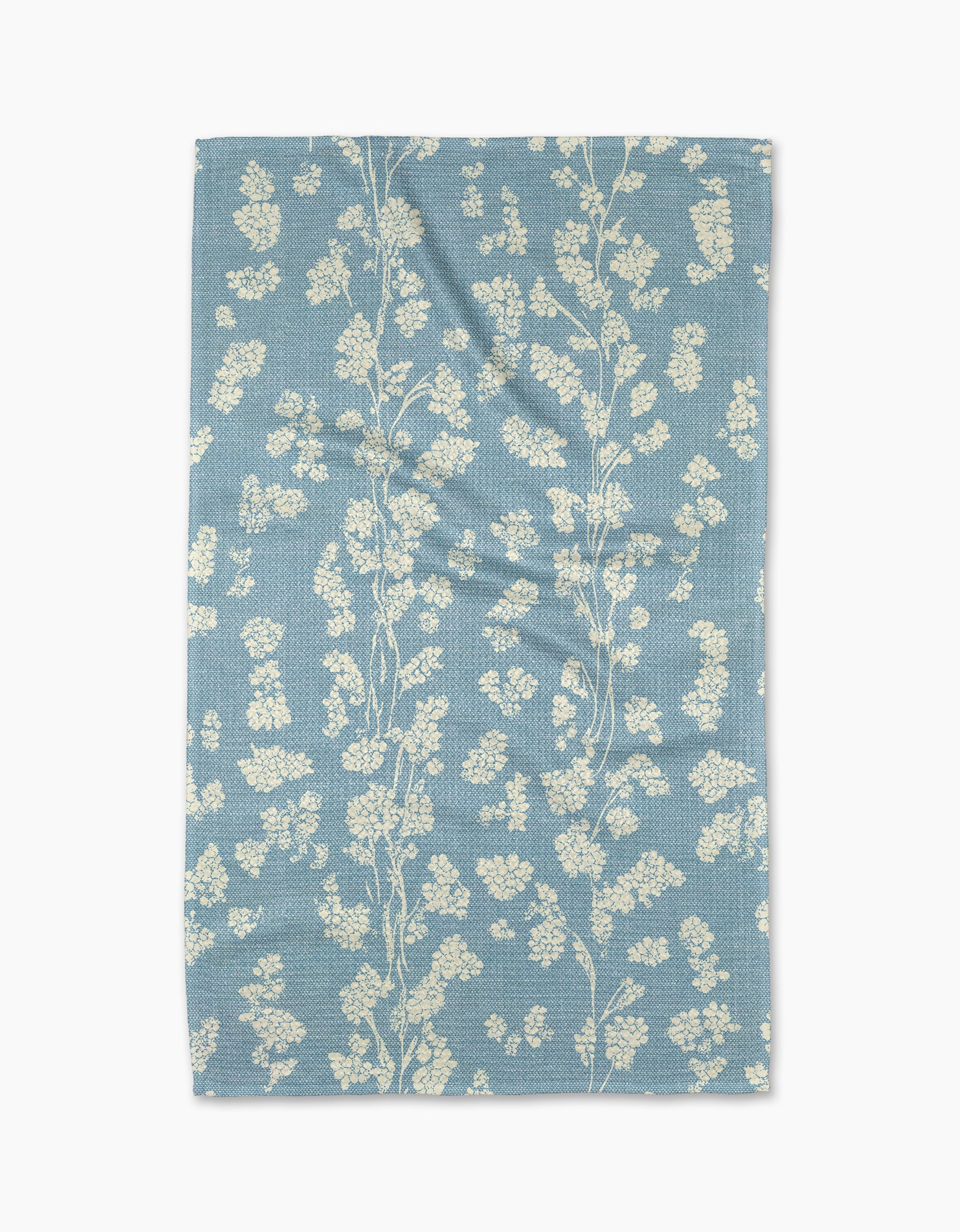 The Geometry Lilou Light Blue tea towel features a delicate white floral pattern on a light blue, ultra-absorbent textured fabric with subtle wrinkles for added charm.