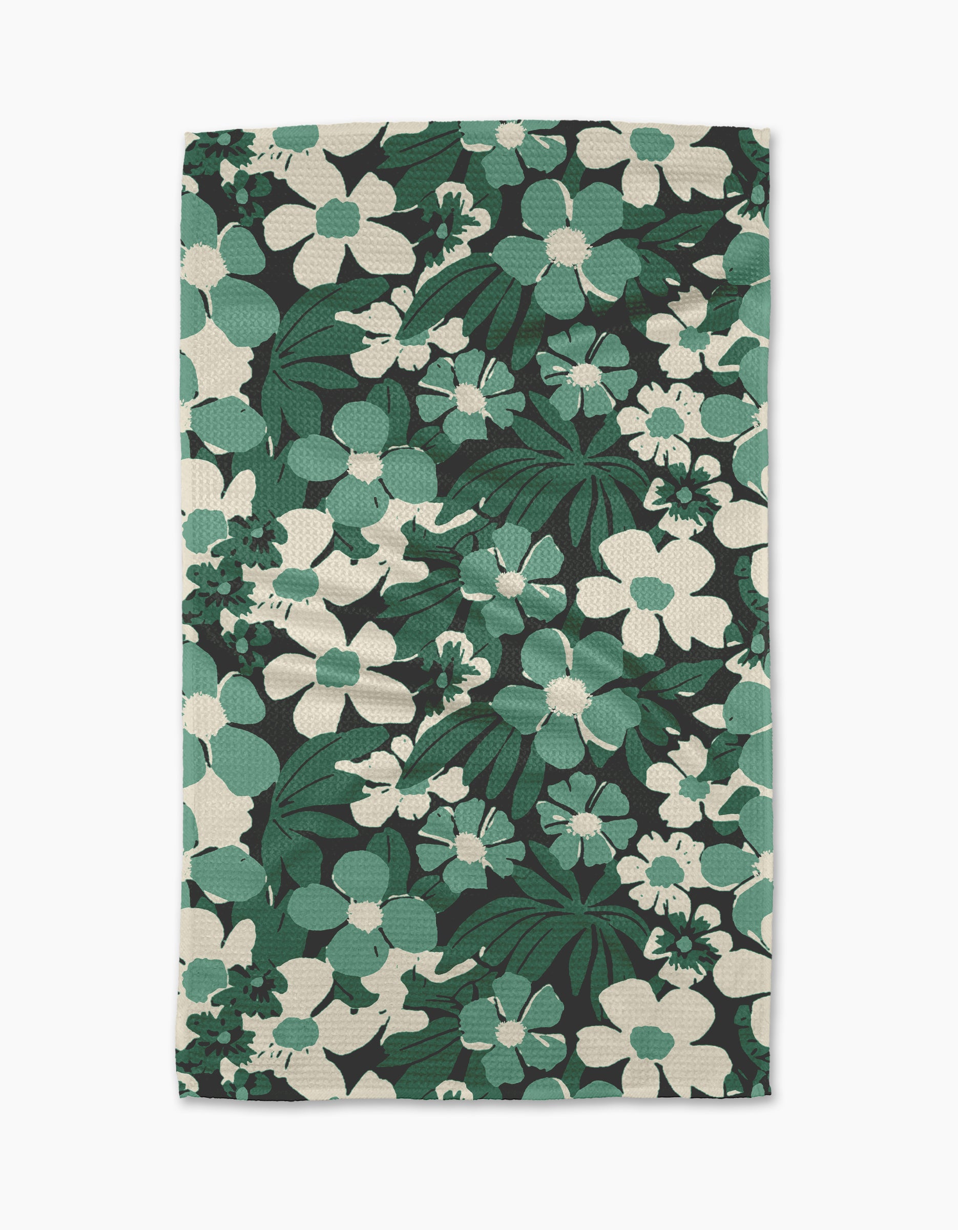 The Geometry Marlo Green tea towel features a bold floral design with large green and white flowers and leaves on a black background. Made from recycled materials, its fabric has a textured, woven look.
