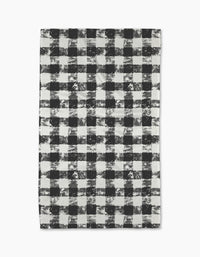 The Geometry Patch Ash tea towel features a black and white buffalo plaid pattern with a distressed, textured look on a white background.
