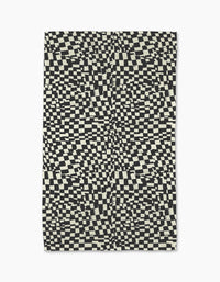 The Static rug by Geometry features a black and white distorted checkerboard pattern for an optical illusion effect—pair it with a modern, eco-friendly kitchen towel for a coordinated look.