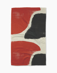 The Geometry Still towel is a rectangular, quick-drying towel featuring an abstract design with bold black and red shapes divided by off-white curved lines on a textured background.