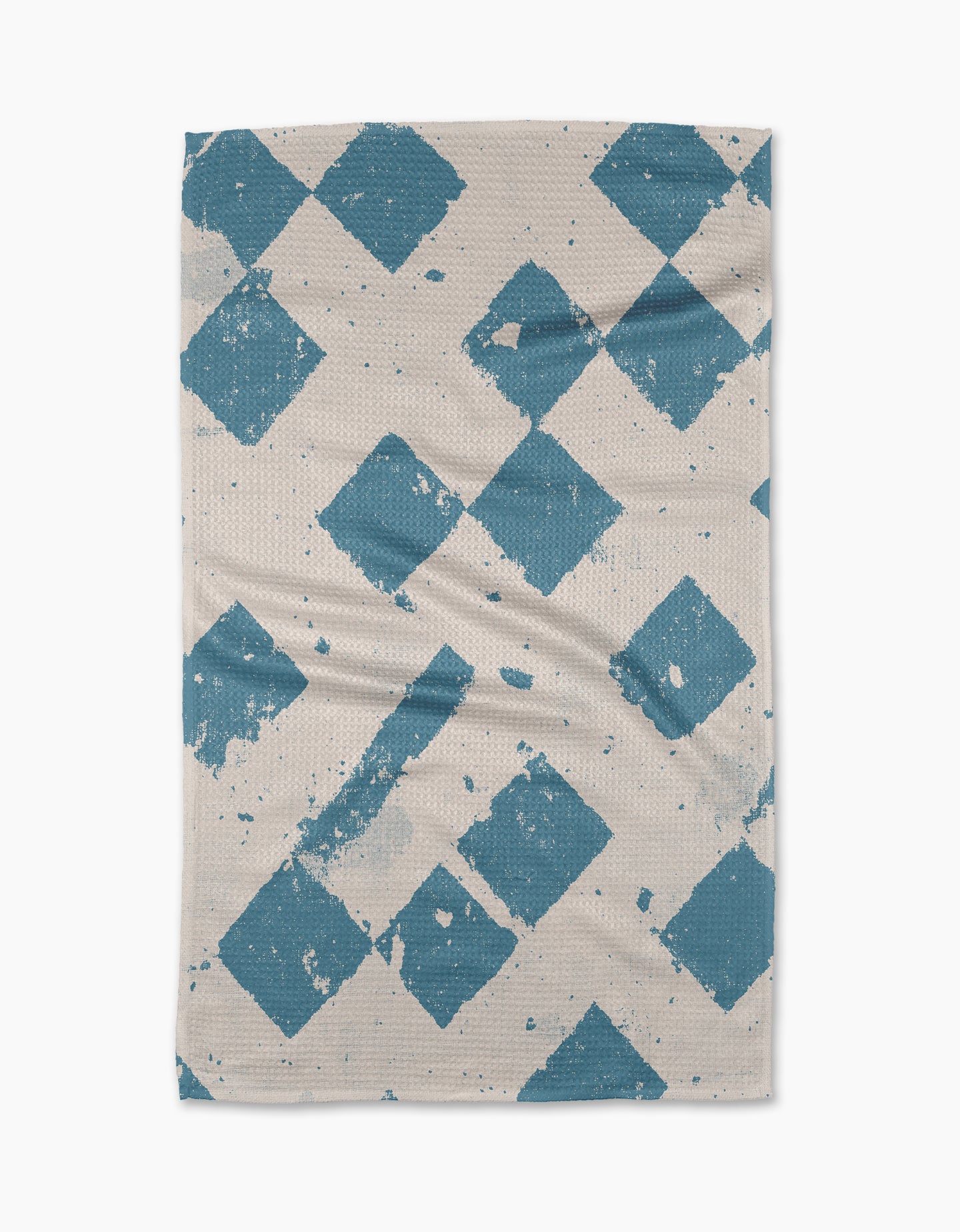 The Geometry Wisp Blue tea towel features large, distressed blue diamonds diagonally across a beige, textured surface. Some faded edges create a vintage look. Made from quick-drying, recycled materials.