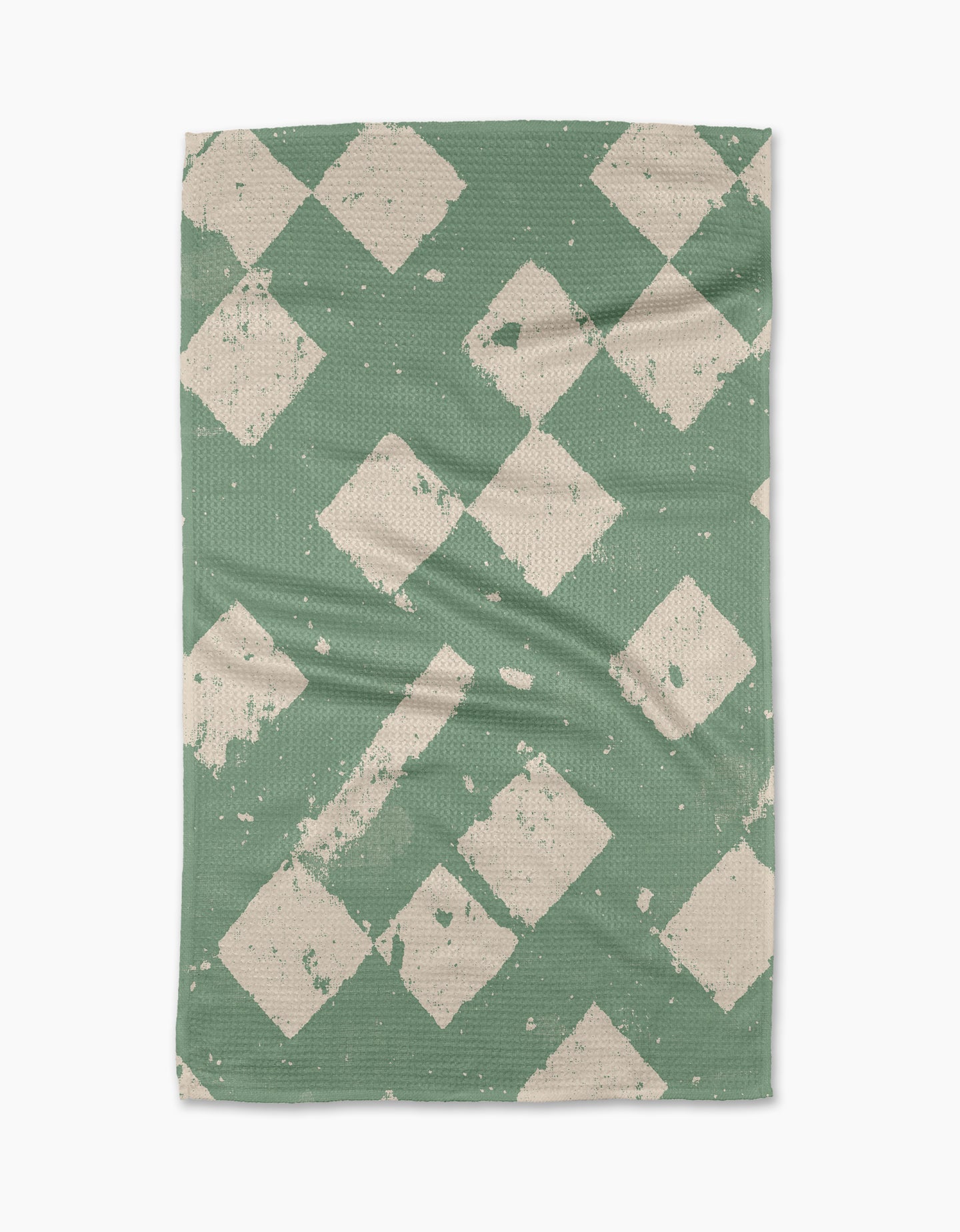 The Geometry Wisp Green tea towel features a textured green background with off-white, distressed diamond patterns. Made from recycled materials, its fabric has gentle creases and visible wear for a charming, lived-in look.