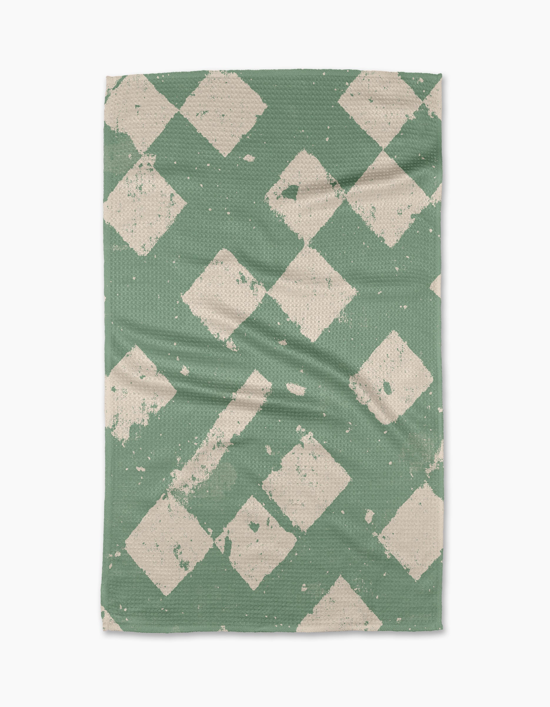The Geometry Wisp Green tea towel features a textured green background with off-white, distressed diamond patterns. Made from recycled materials, its fabric has gentle creases and visible wear for a charming, lived-in look.
