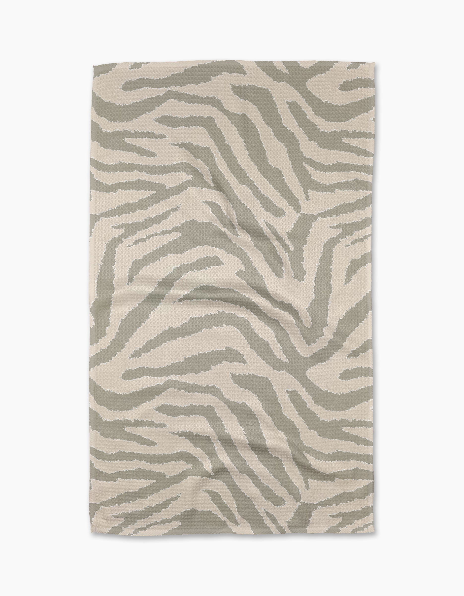 The Zira Gray tea towel by Geometry is a beige, rectangular cloth made from recycled materials, featuring a subtle abstract light gray zebra stripe pattern. The towel is shown laid flat on a white background.