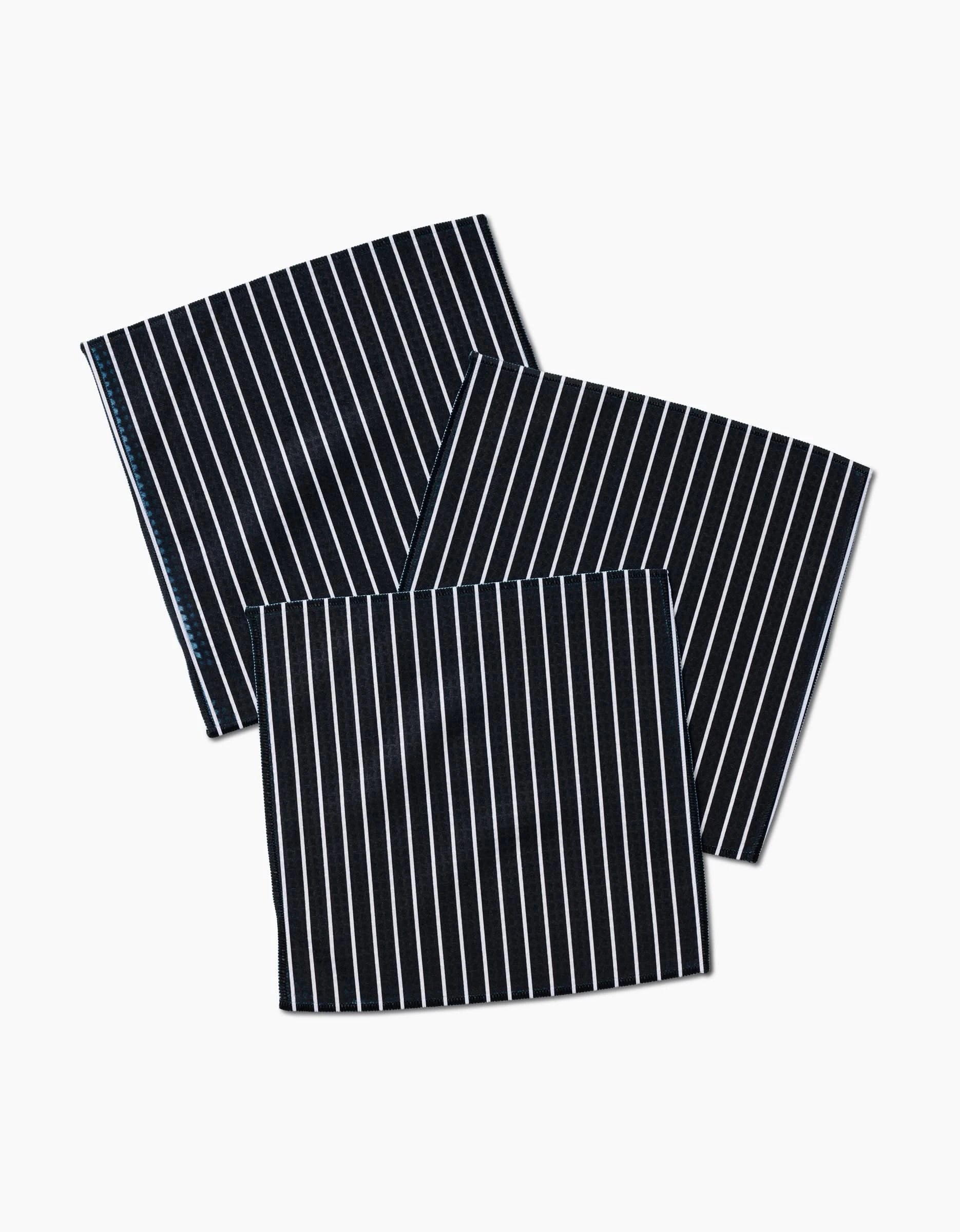 Three GEOMETRY Black Linen washcloths, featuring thin white vertical stripes and ultra-absorbent Geoweave technology, are neatly arranged and slightly overlapping on a white background.