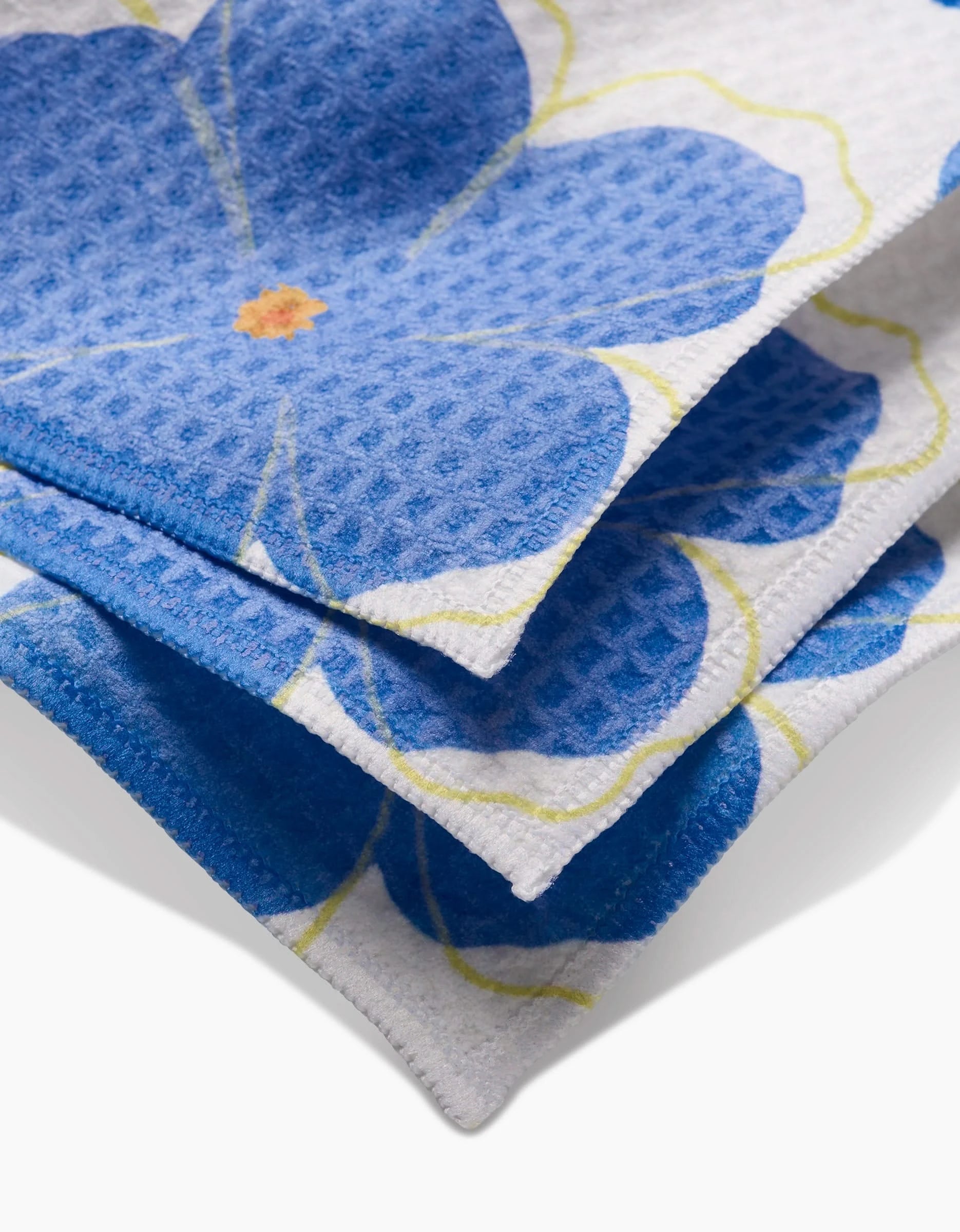 Close-up of Blue Blossoms Luxe Washcloth towels by Elana Gabrielle—soft, ultra-absorbent, with a textured white finish and blue floral pattern. Neatly folded, they offer stylish design paired with excellent functionality.