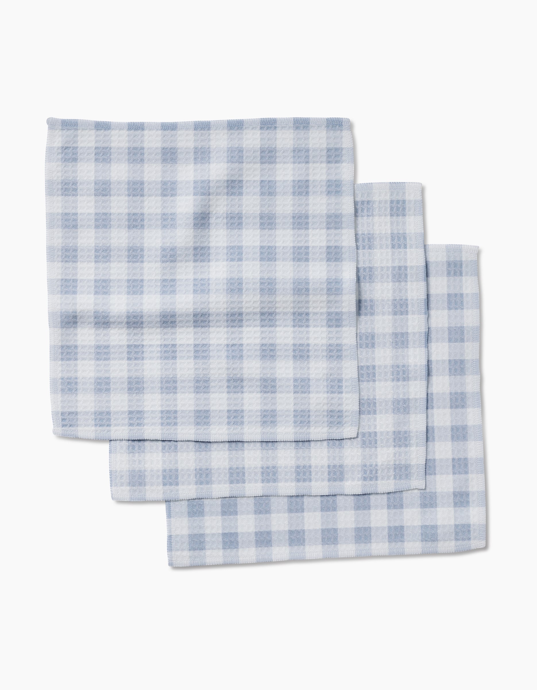 Three Blue Gingham cloth napkins by Aubrey Fairchild, featuring ultra-absorbent Geoweave technology, are neatly stacked and slightly overlapping against a white background.
