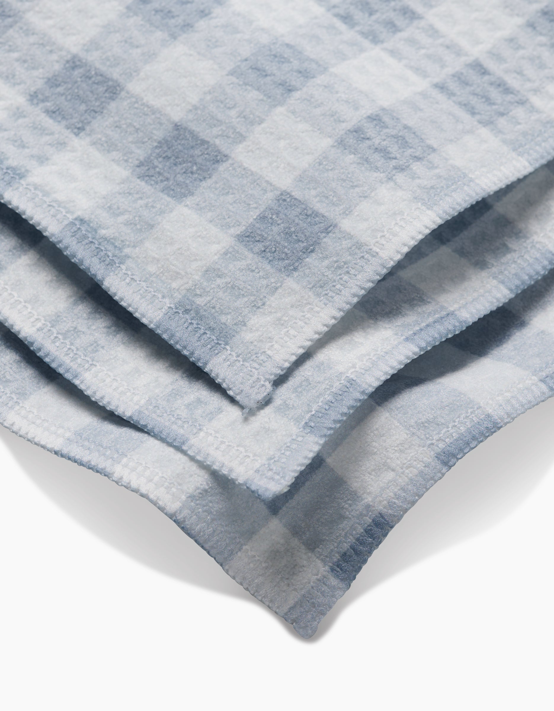 A close-up of the Aubrey Fairchild Blue Gingham washcloths, featuring soft light blue and white checks with visible edge stitching, highlights their ultra-absorbent Geoweave technology.