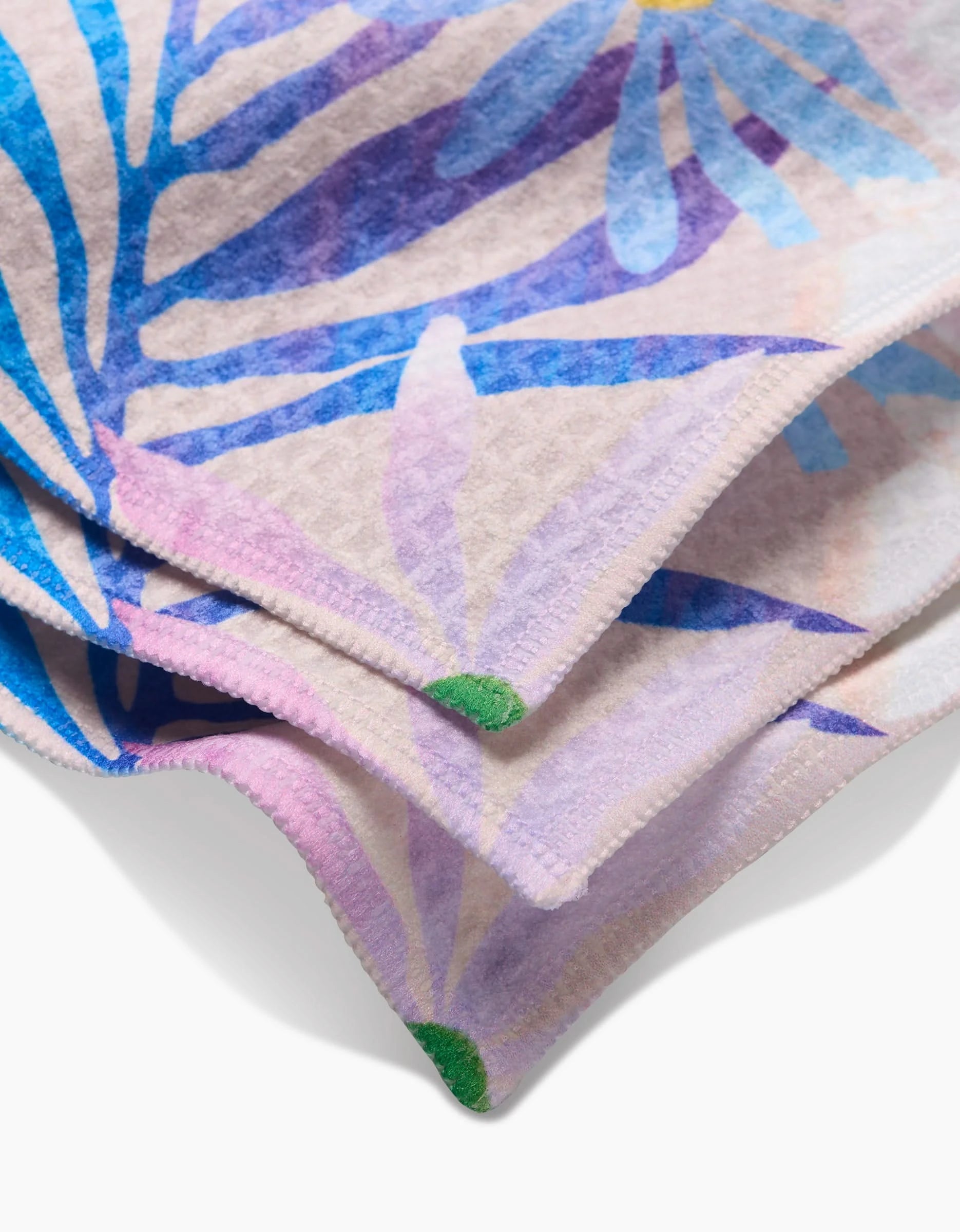 A close-up of two GEOMETRY Bold Blossoms washcloths, showcasing a colorful blue, purple, and green abstract floral pattern with ultra-absorbent textured fabric and neatly stitched edges.