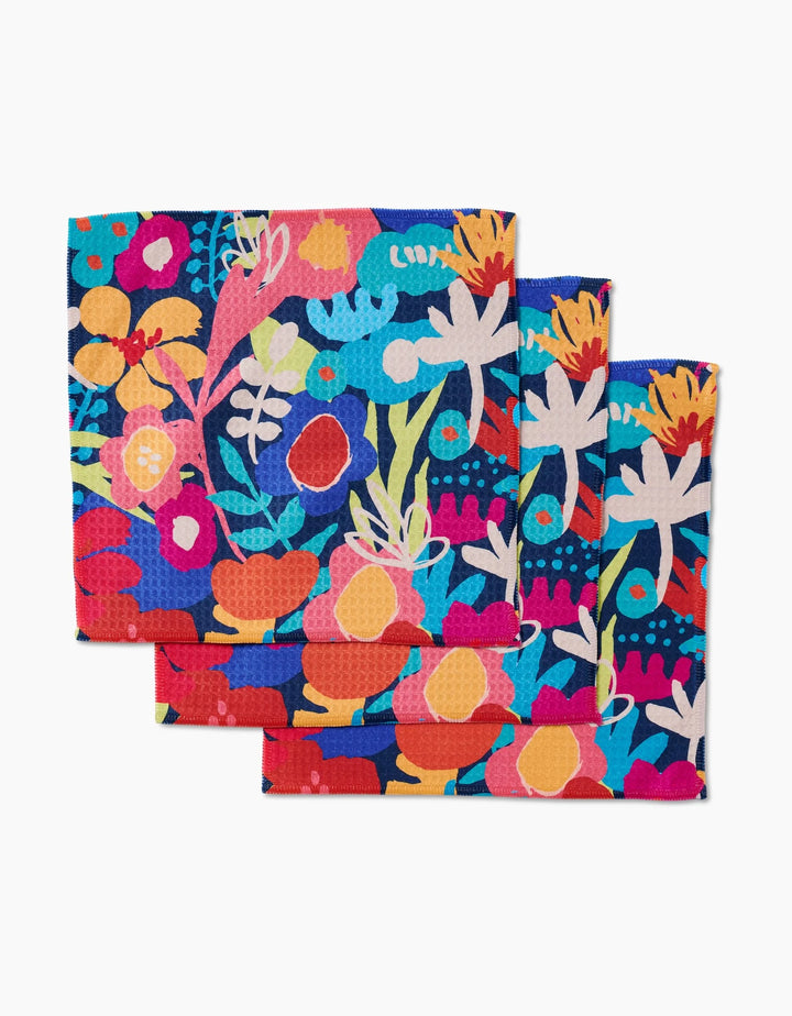 Three Bright Bunch washcloths by Sareka Unique, featuring a vibrant abstract floral design in blue, orange, pink, yellow, and white, are arranged overlapping and crafted with Geoweave technology for superior absorbency.