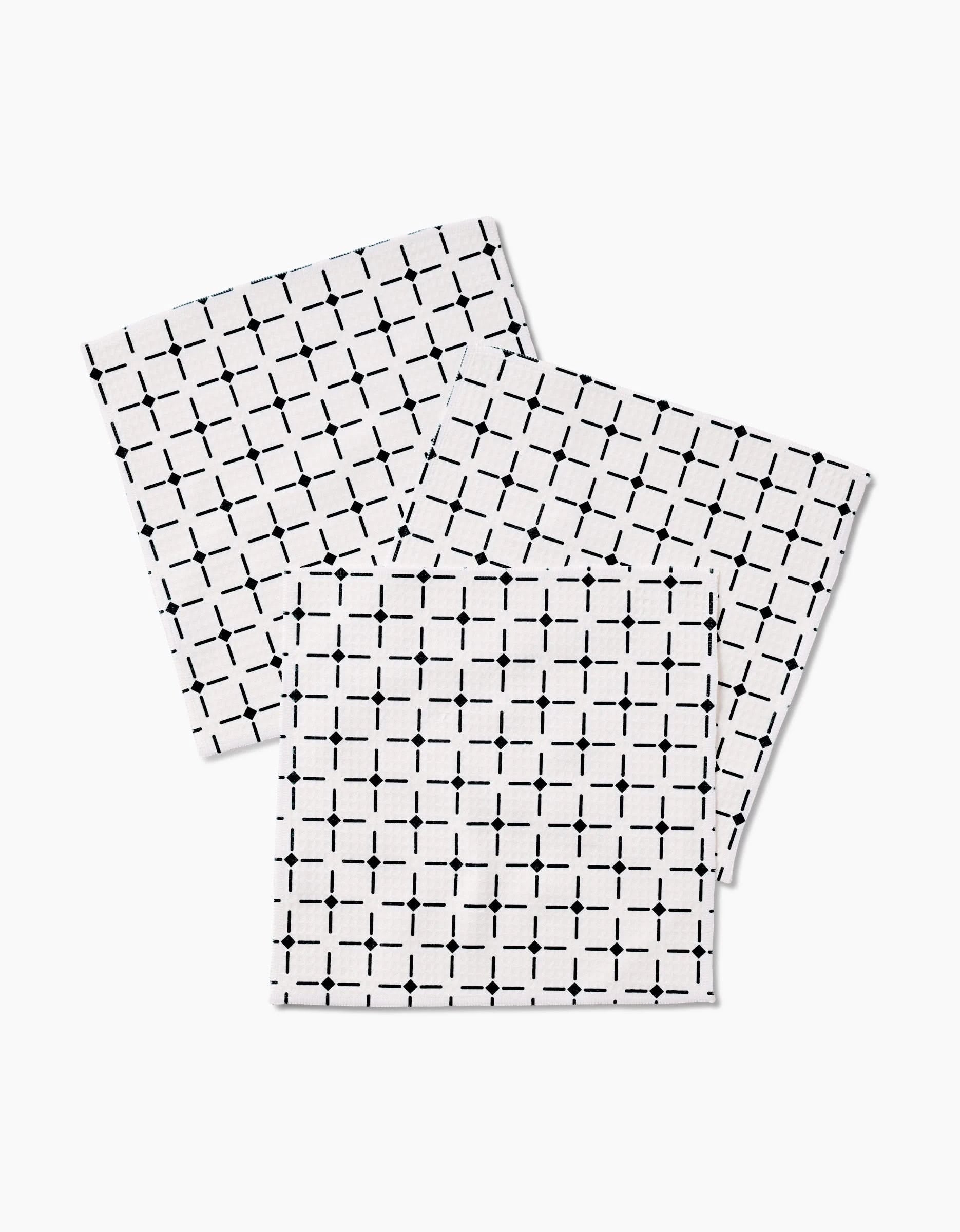 Three white Collins washcloths by Charlie Rowan Designs, featuring a black grid with dotted intersections, are stacked on a white background. Made with ultra-absorbent Geoweave technology for superior cleaning.