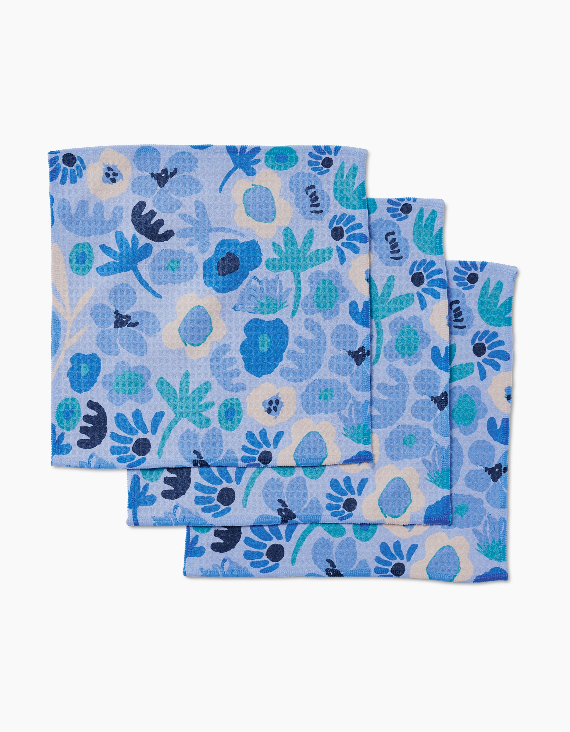 Three folded Cool Blooms napkins by Sareka Unique, featuring a blue floral and leaf pattern on a light blue background, are arranged slightly overlapping and made with ultra-absorbent Geoweave technology for superior performance.