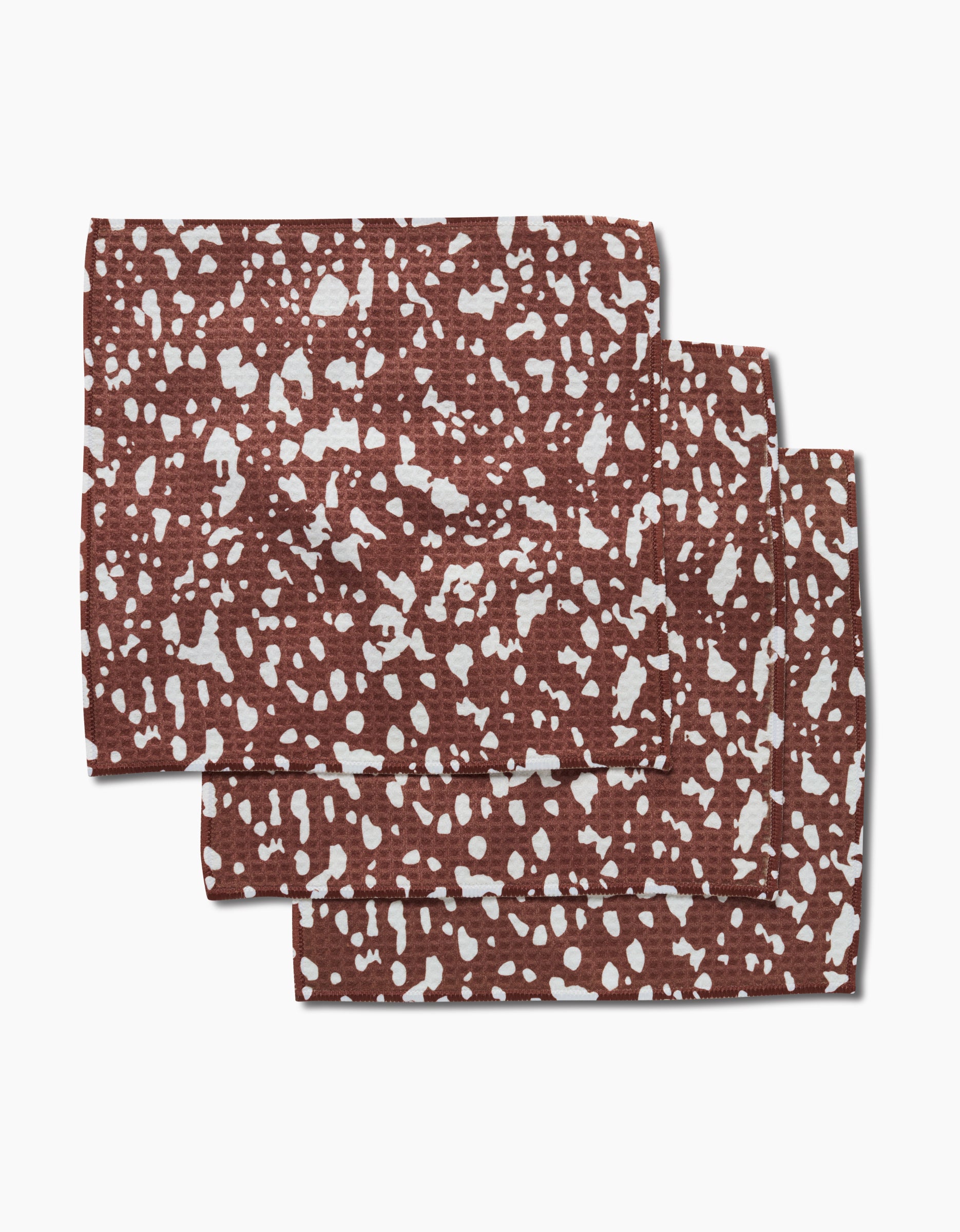 Three folded Cowboy Horse Hide napkins by Hufton Studio, featuring an irregular white speckled pattern, are stacked on a white background. Made with Geoweave technology, these linens offer ultra-absorbent everyday elegance.