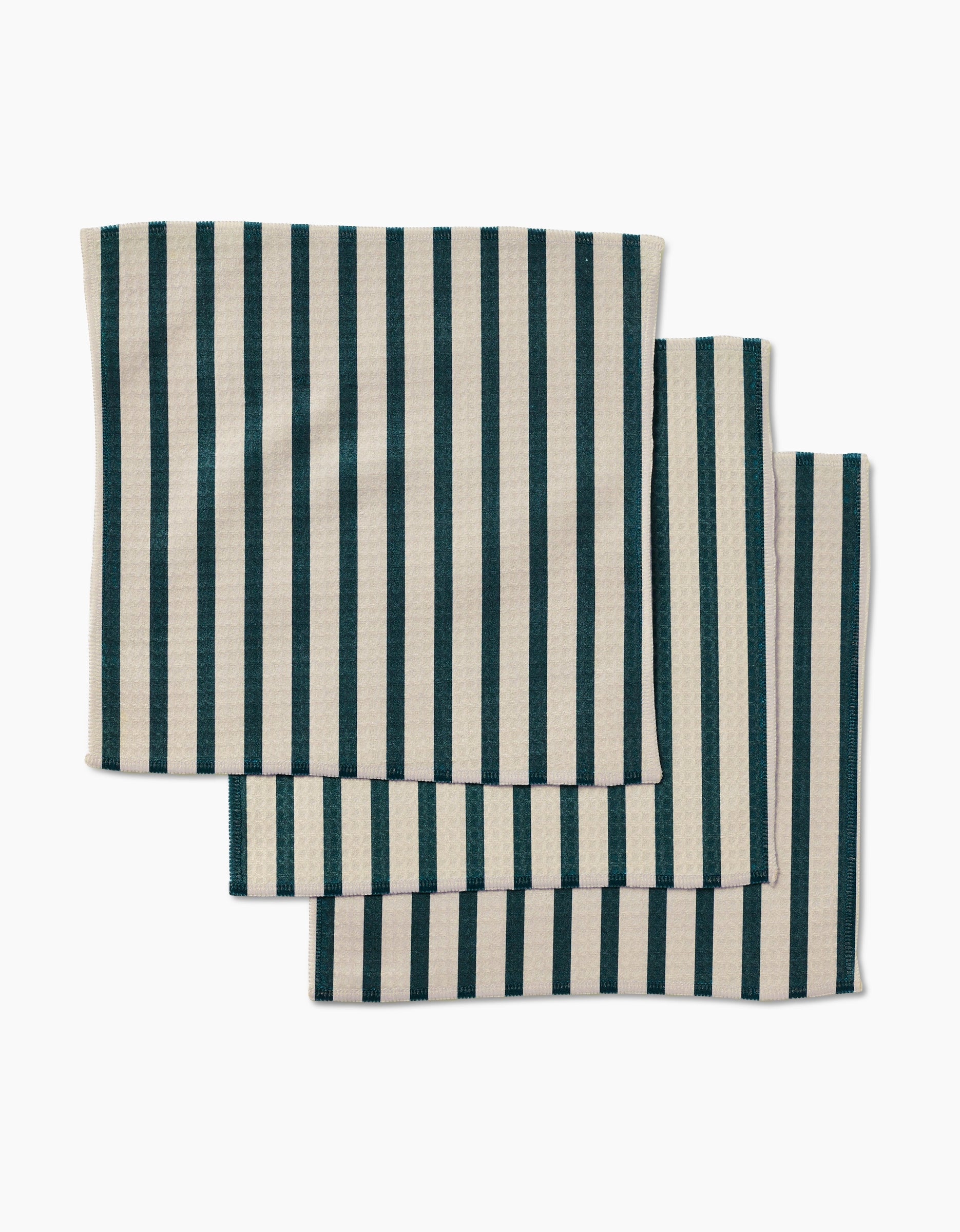 Three GEOMETRY Deep Green Stripes napkins, beige with vertical dark green stripes and made from post-consumer recycled materials, are stacked neatly and slightly overlapping on a white background.