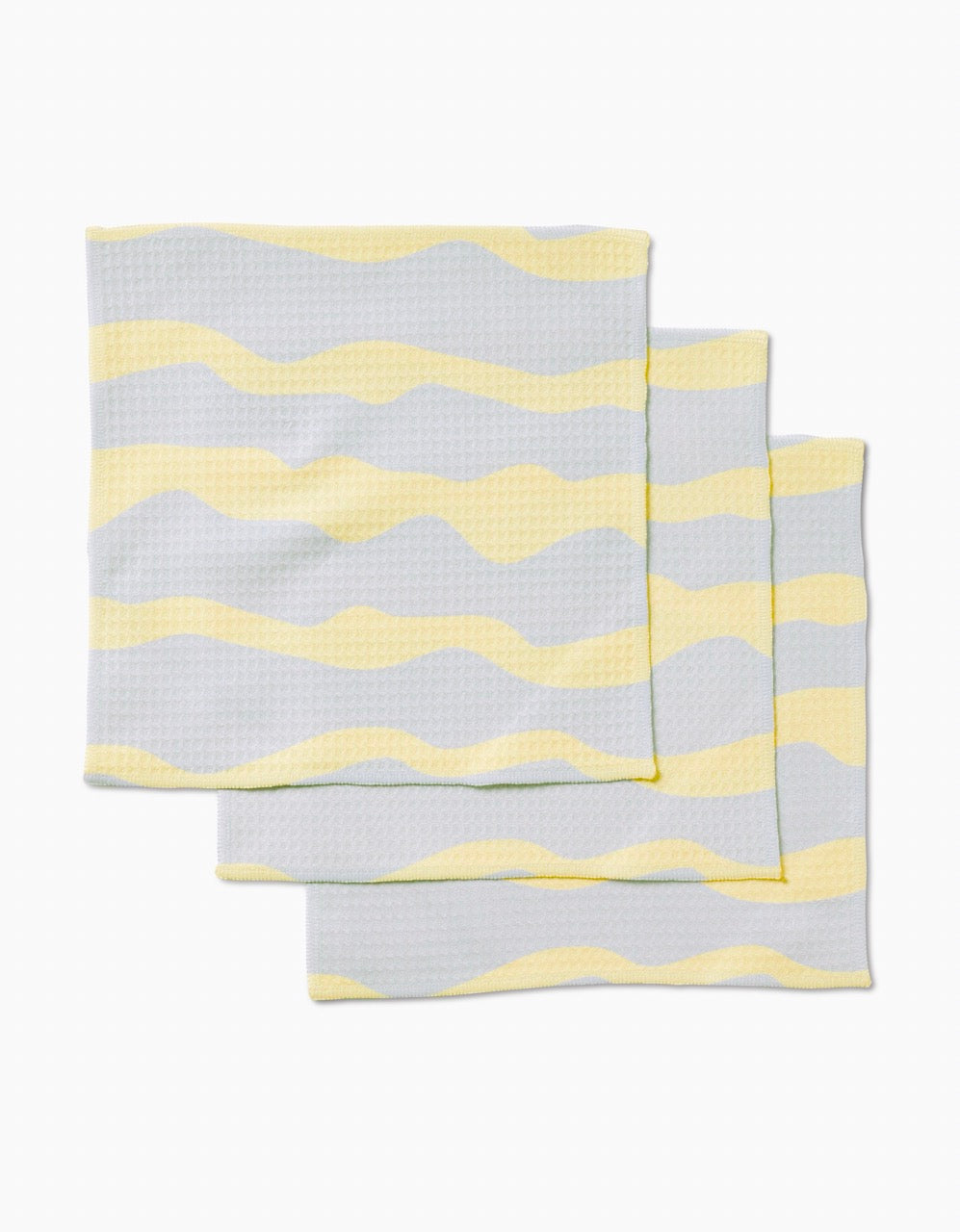 Three folded GEOMETRY Eclipse Twist washcloths with wavy yellow and gray stripes, stacked on a white background. Made with Geoweave technology, theyre ultra-absorbent for everyday luxury.